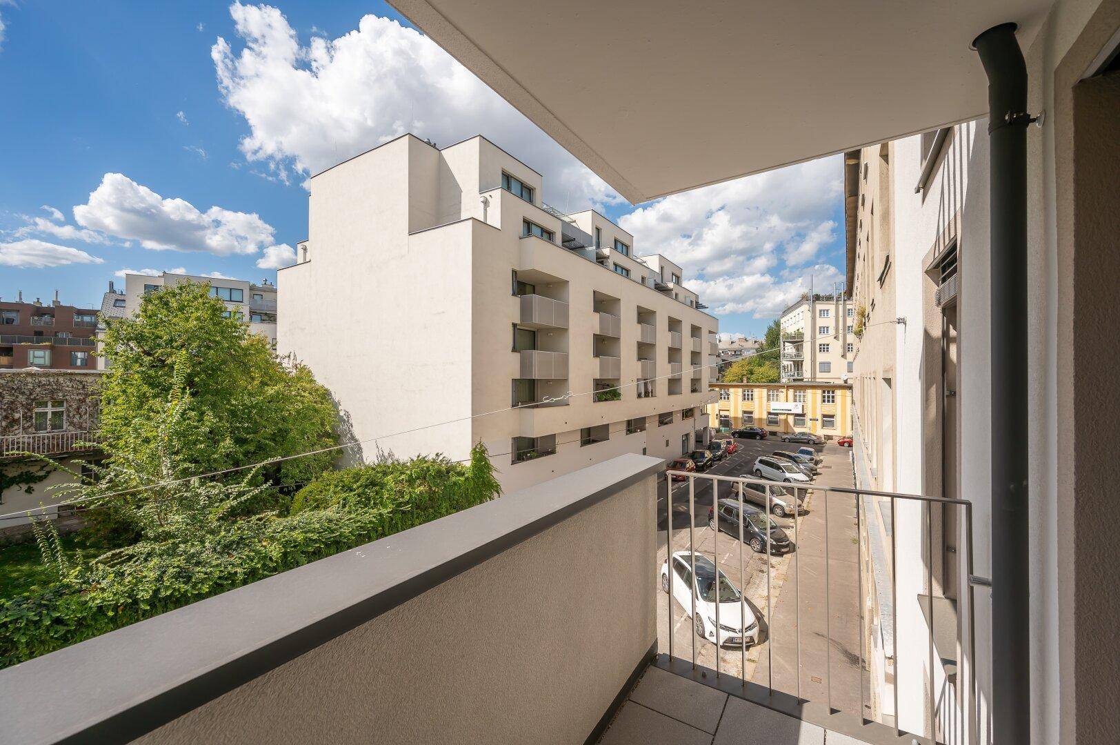 Balkon mit Blick auf die umliegenden Gebäude und einen Parkplatz.