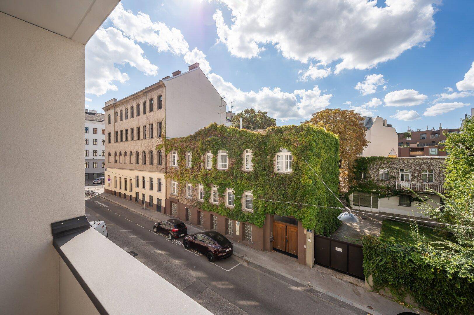 Balkon mit weitem Blick auf eine begrünte Fassade und die Stadtstraße.