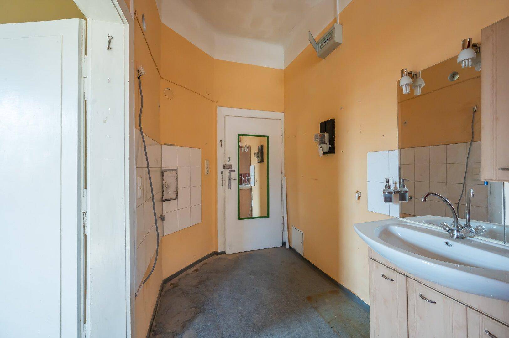 Badezimmer mit Waschbecken, Spiegel und einer Tür, die zu einem anderen Bereich führt.