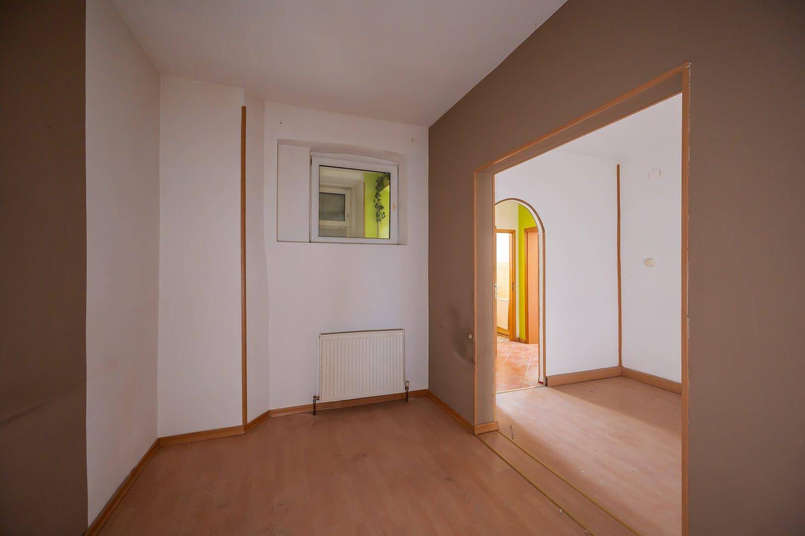 Leerer Raum mit Holzboden und brauner Akzentwand, bietet Potenzial für verschiedene Nutzungen.