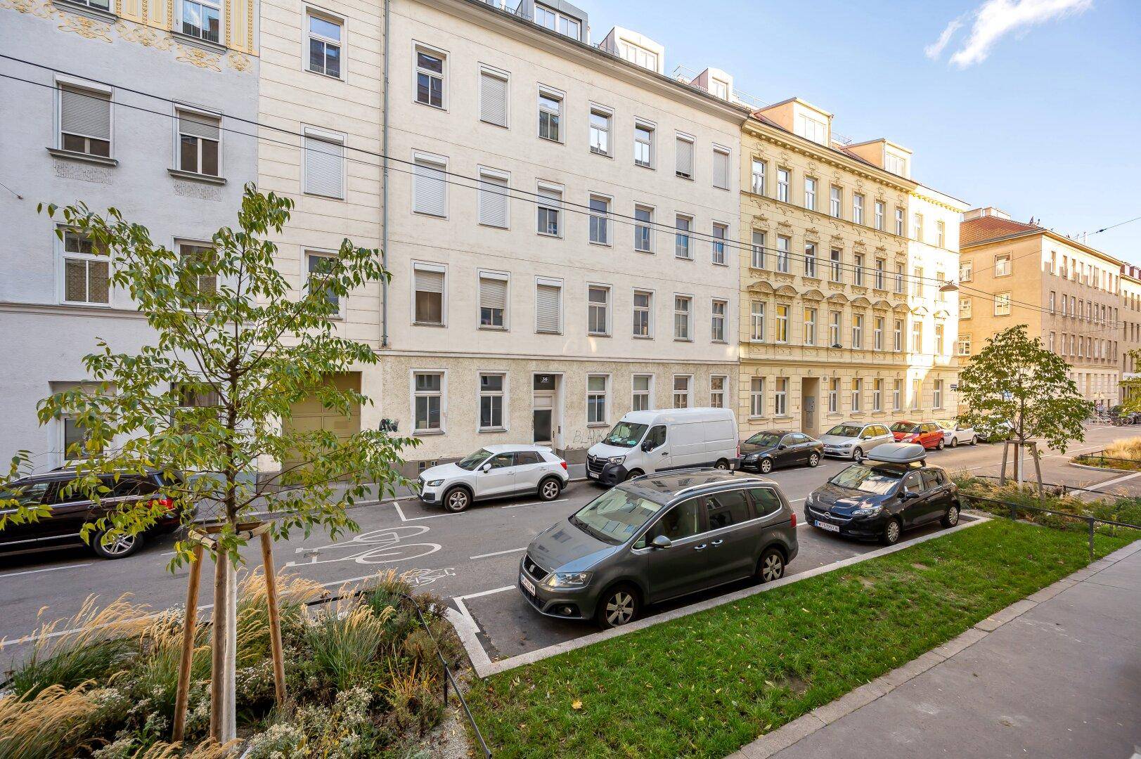Straßenansicht mit parkenden Autos und Gebäuden in einer städtischen Umgebung.