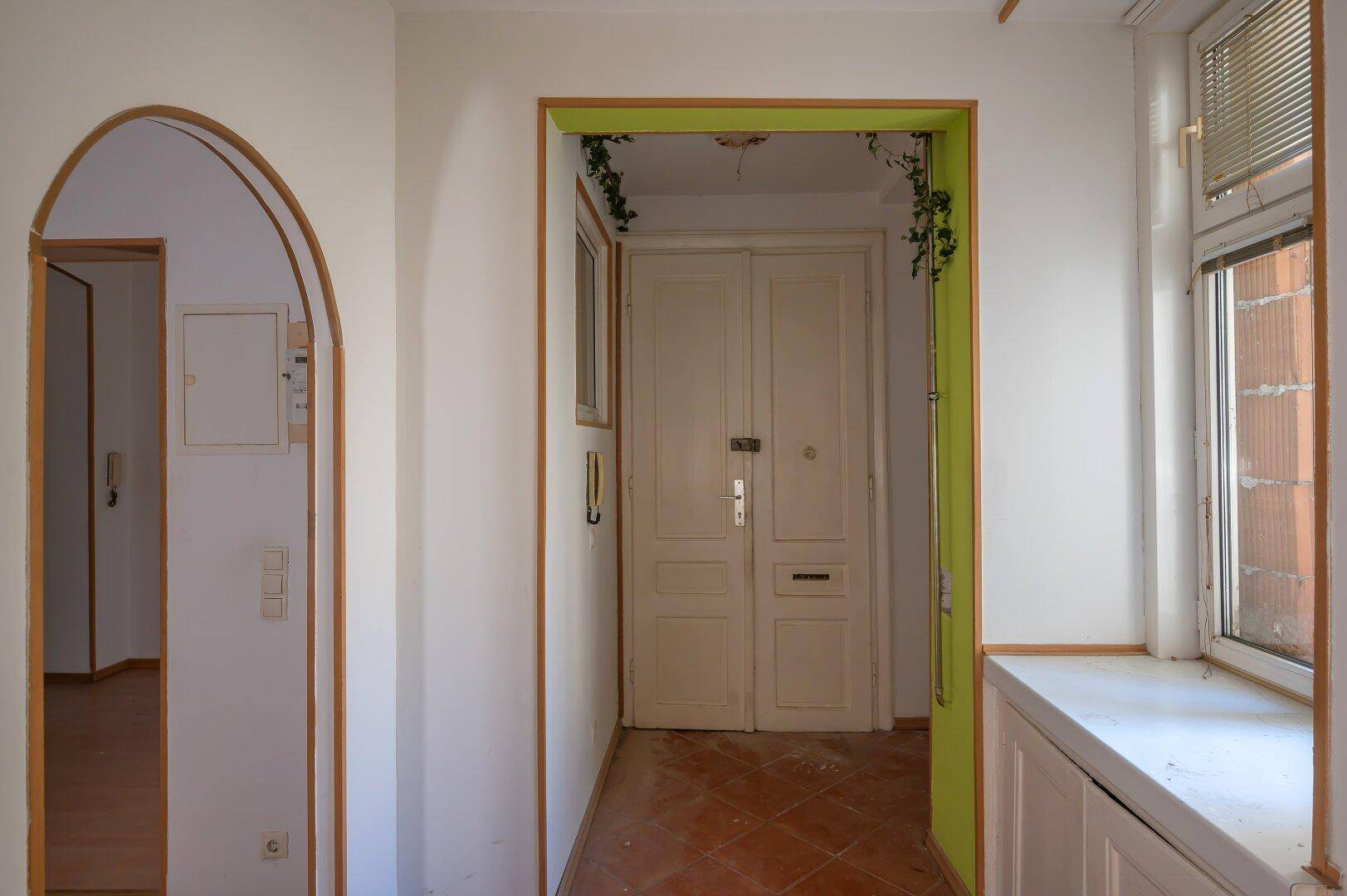 Eingangsbereich mit Terrakottafliesen und doppelter Eingangstür, führt in die Wohnung.