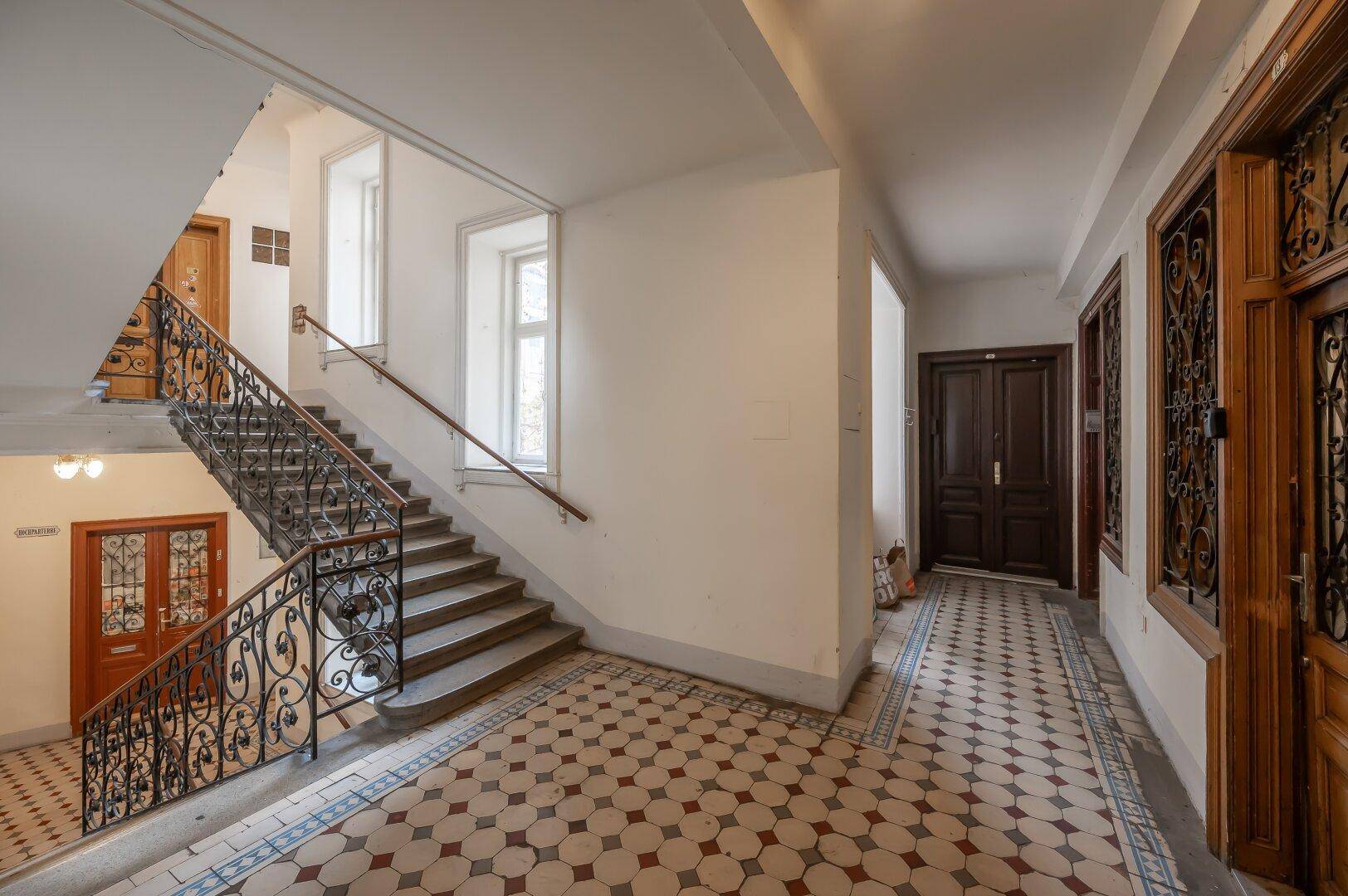 Geräumiges Treppenhaus mit Tageslicht, traditionellem Fliesenboden und elegantem Geländer.