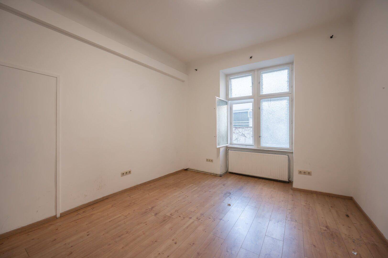Geräumiges Zimmer mit Holzfußboden und einem geöffneten Fenster, ideal für individuelle Gestaltung.