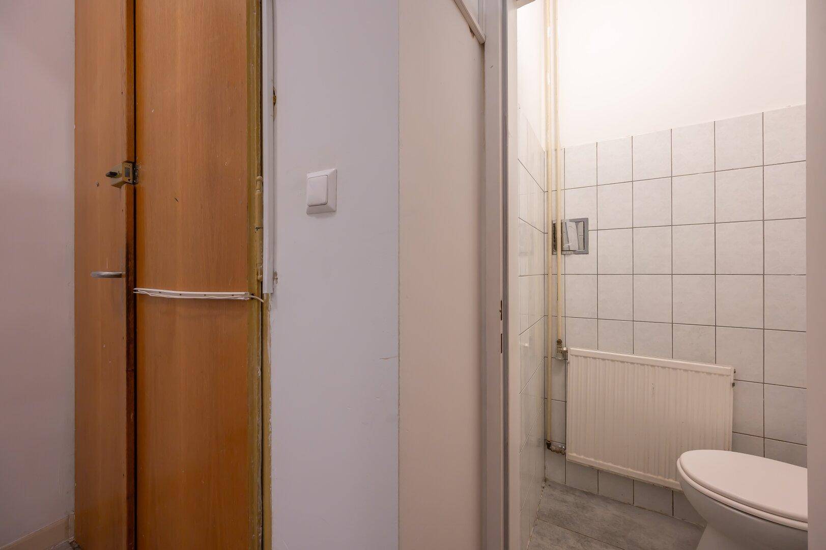 Kleines WC mit Fliesen an den Wänden und einem Heizkörper, funktional und sauber.