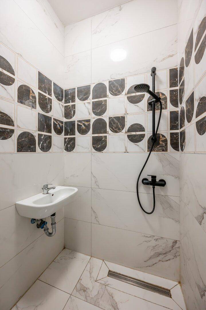 Elegantes Badezimmer mit begehbarer Dusche, Waschbecken und modernen Marmorfliesen.