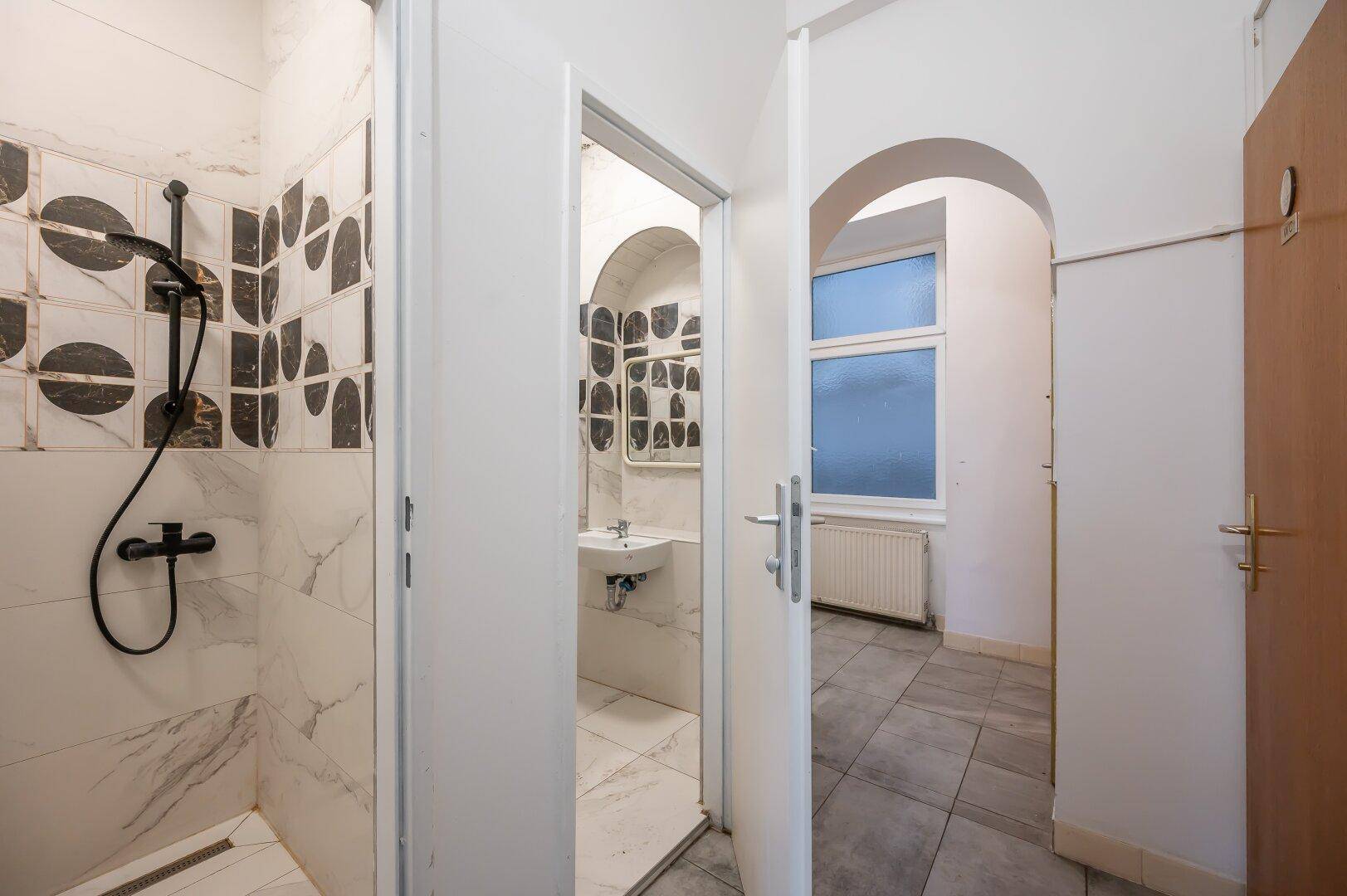 Modernes Badezimmer mit begehbarer Dusche, Waschbecken und dekorativen Fliesen.