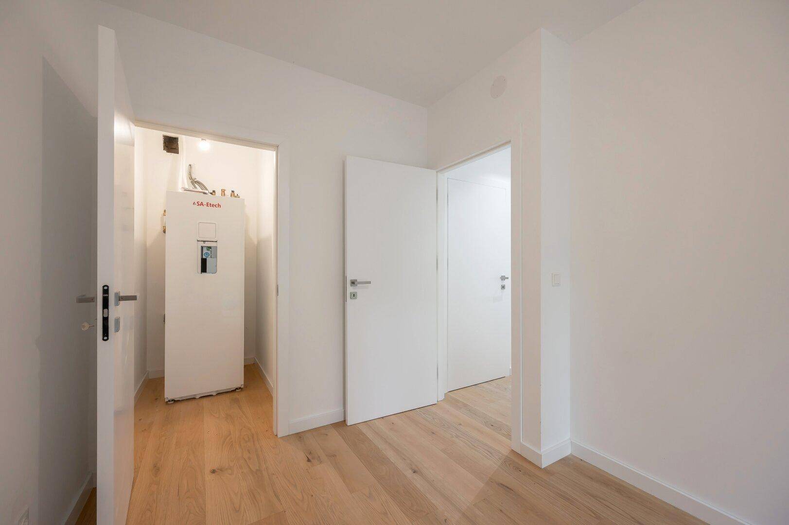 Praktischer Hauswirtschaftsraum mit Heizungsanlage und Holzfußboden.