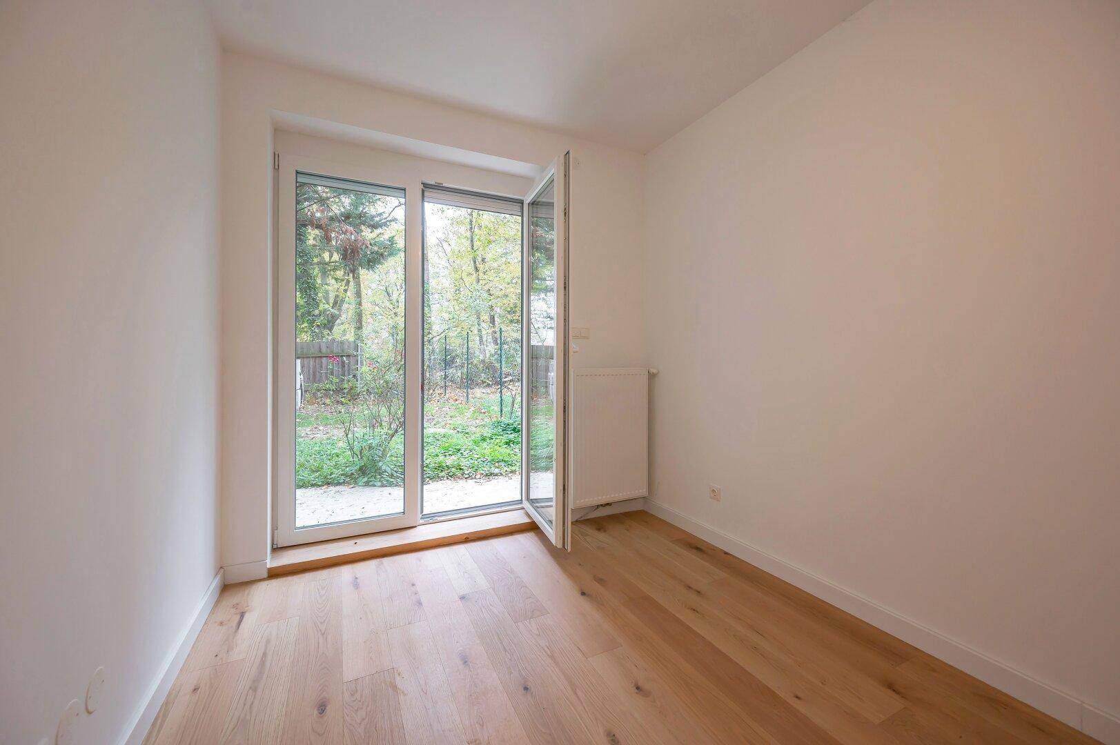 Helles Zimmer mit Parkettboden und direktem Zugang zum Gartenbereich.