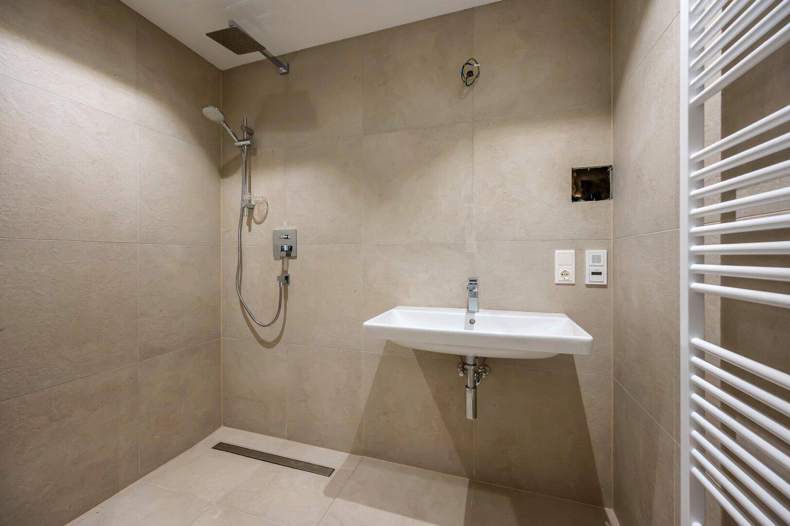 Modernes Badezimmer mit ebenerdiger Dusche, Regendusche und eleganten Fliesen.