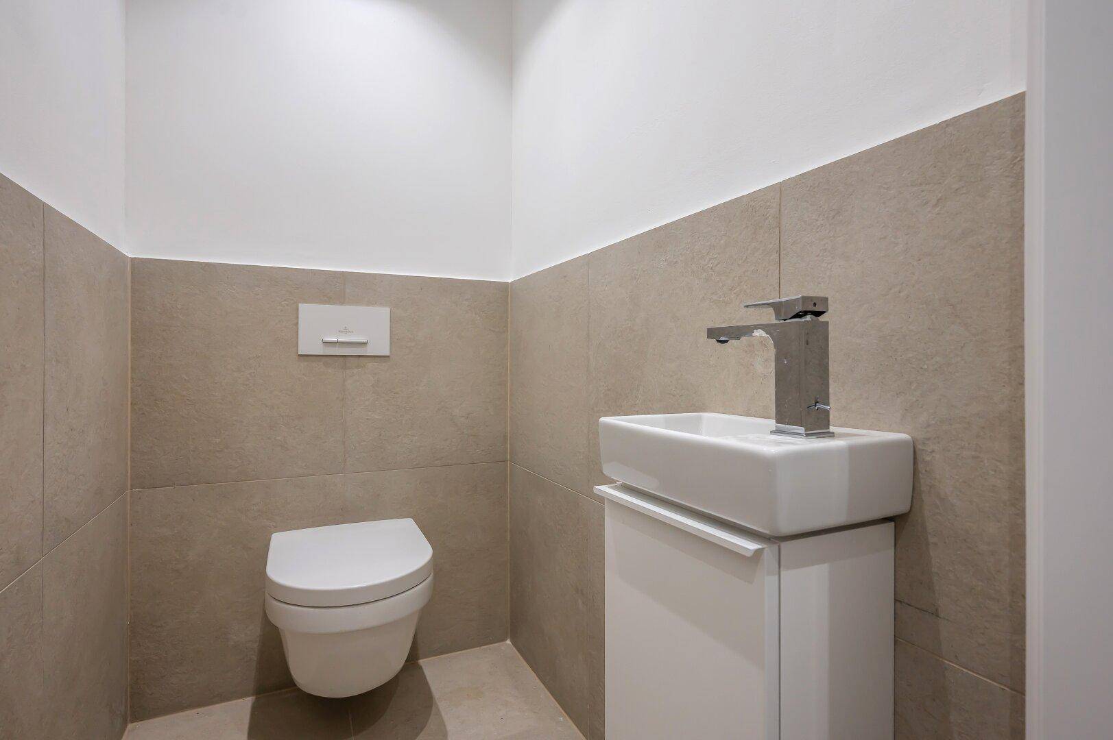 Gäste-WC mit modernen Fliesen, wandhängendem WC und kleinem Waschbecken.