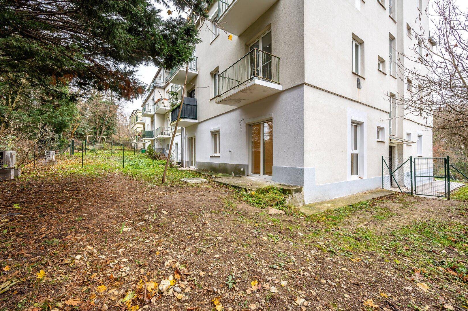 Außenseite eines Mehrfamilienhauses mit Balkonen und umgebendem Grün.