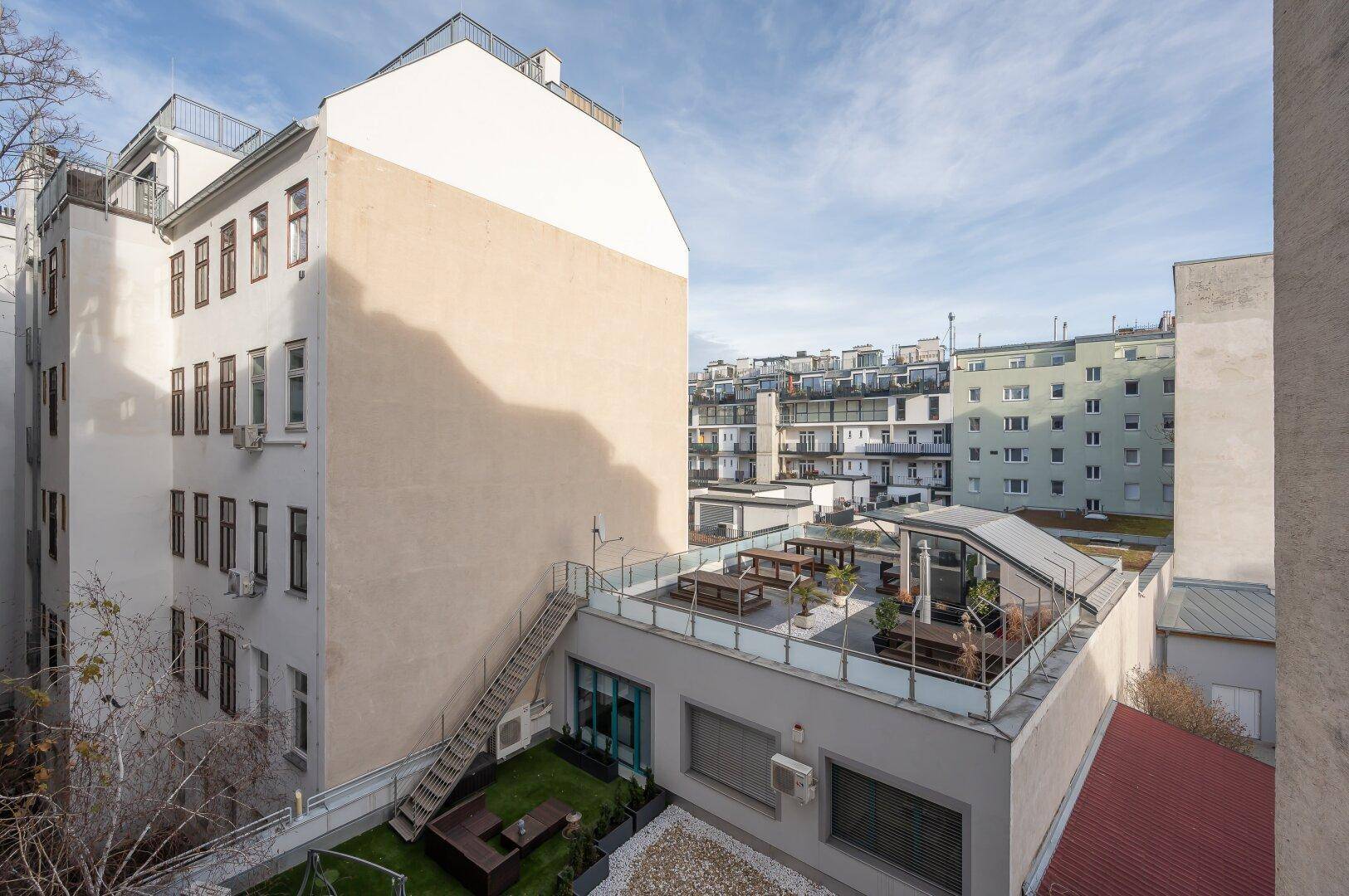 Dachterrasse mit Sitzgelegenheiten und Blick auf die umliegenden Gebäude der Stadt.
