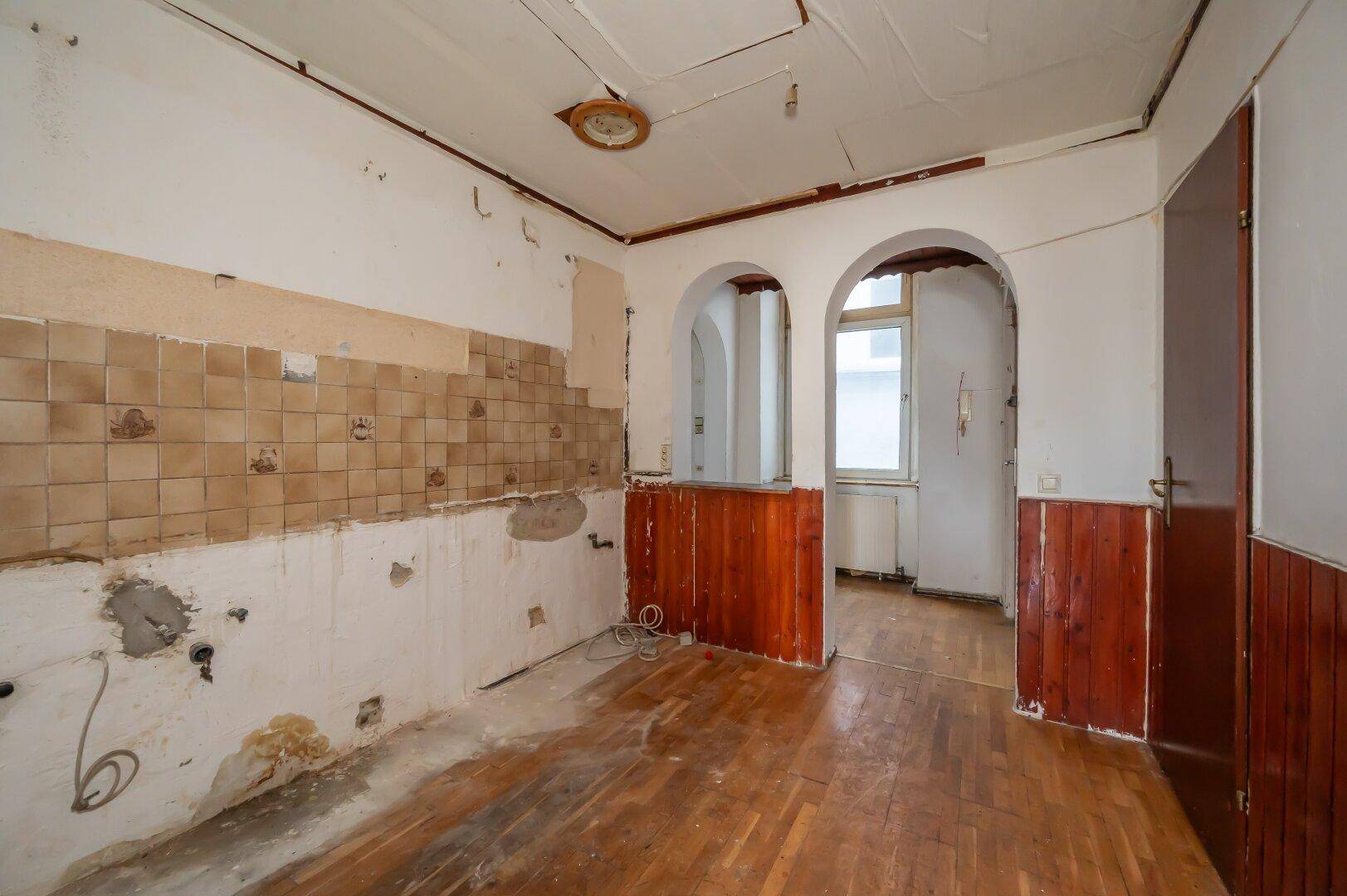 Renovierungsbedürftige Küche mit alten Fliesen und Holztäfelung, bereit für eine Neugestaltung.