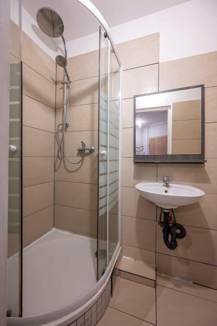 Modern gefliestes Badezimmer mit Duschkabine, Waschbecken und Spiegel, hell und funktional.