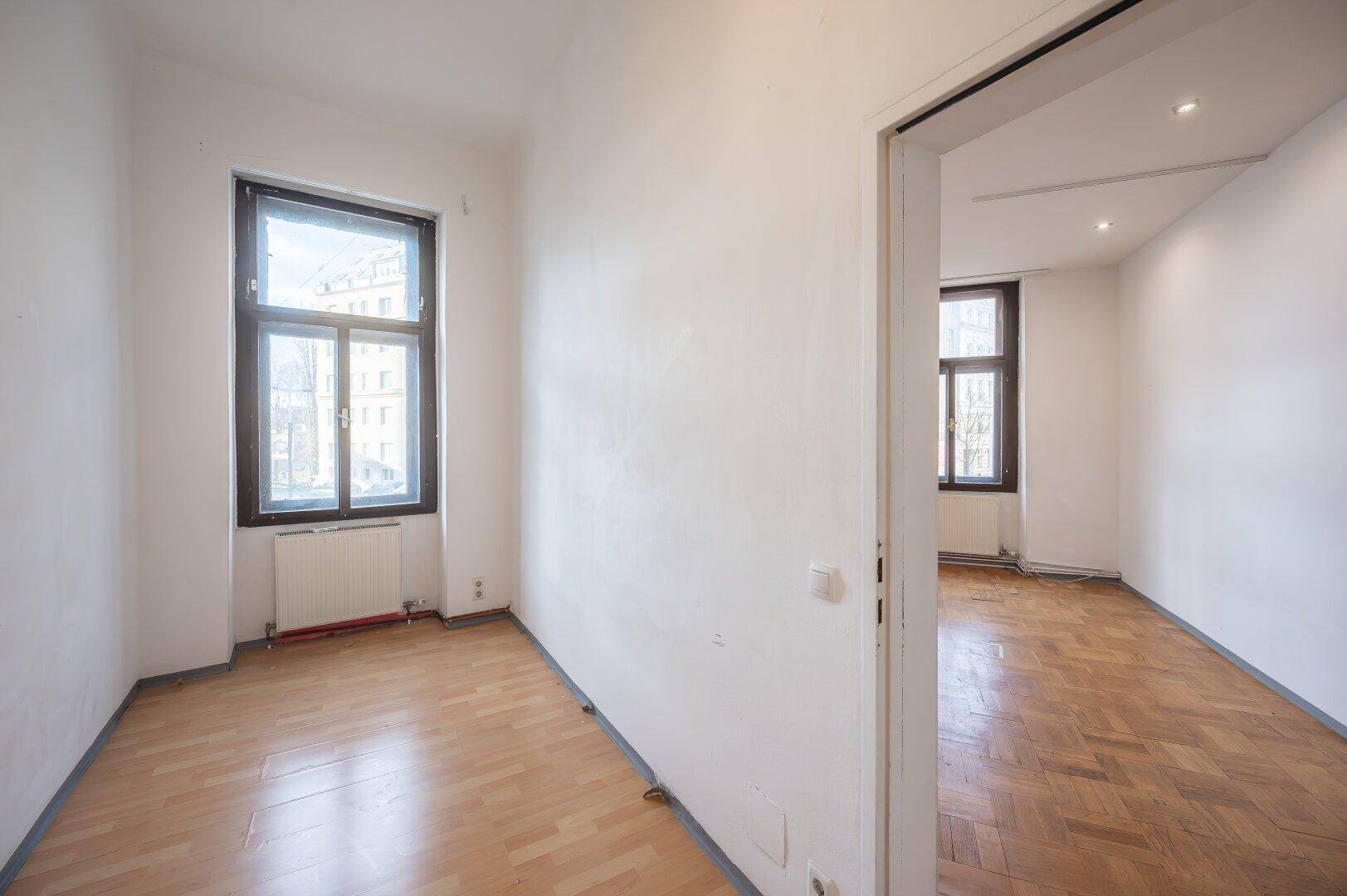 Helles, leeres Zimmer mit Parkettboden und Fenster, geeignet als Schlafzimmer oder Büro.