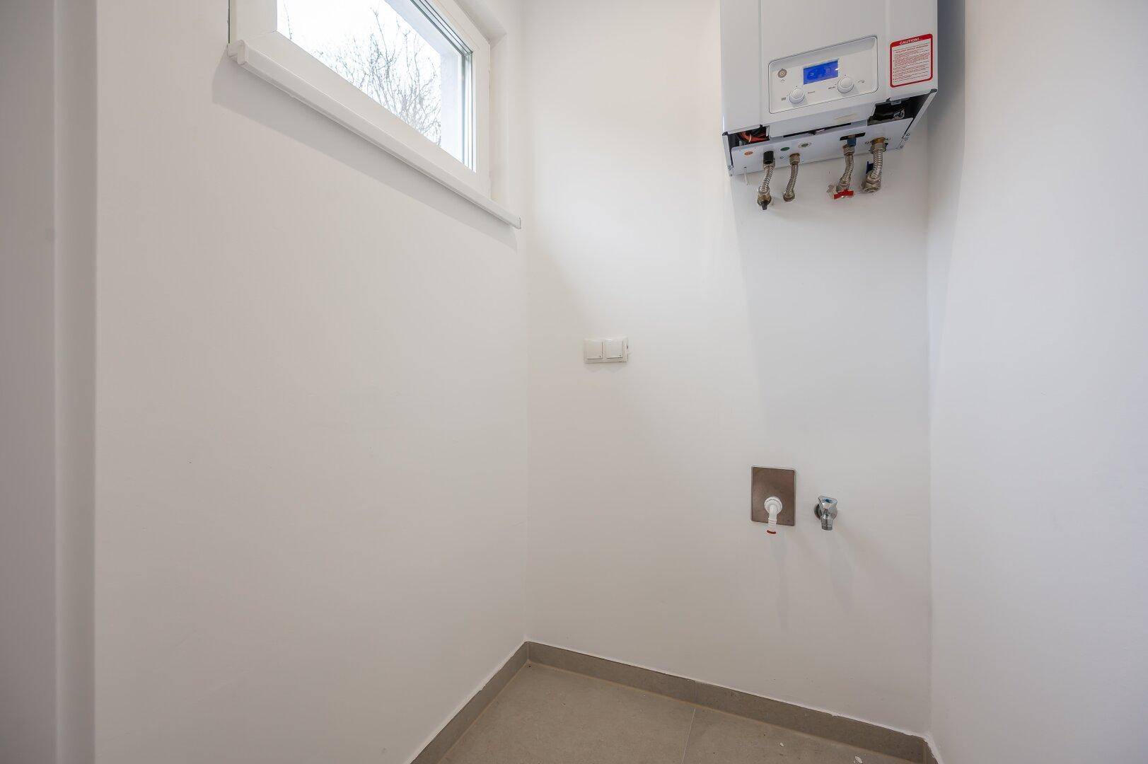 Hauswirtschaftsraum mit Heizungsanlage, Fenster und Anschlüssen für Waschmaschine.