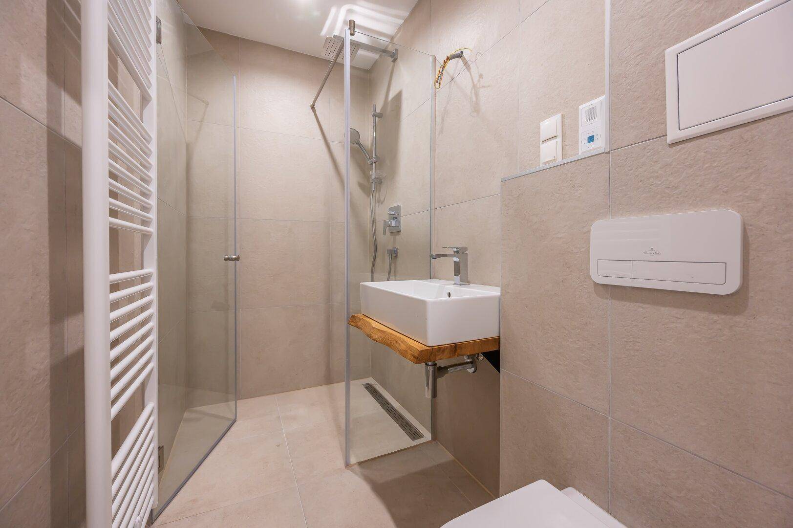 Modernes Badezimmer mit ebenerdiger Dusche, Wand-WC und stilvollem Waschbecken.