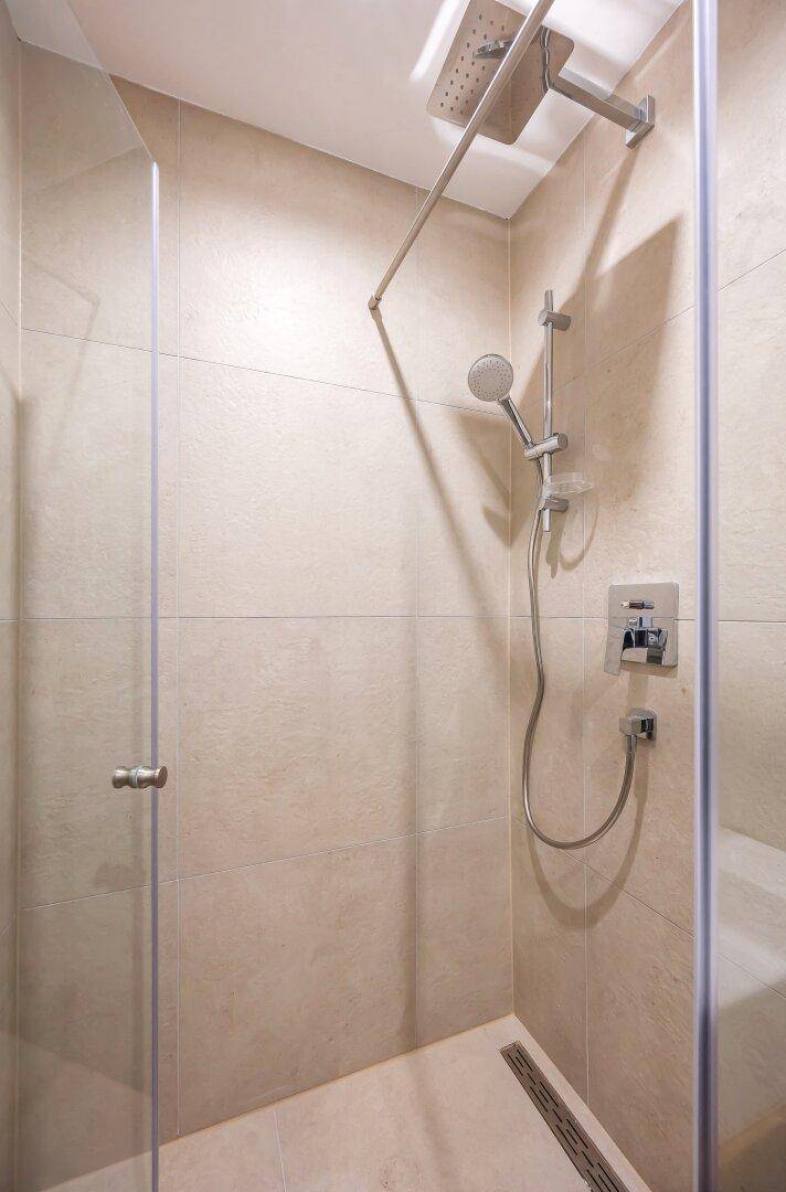 Ebenerdige Dusche mit Glasabtrennung und moderner Regendusche im Badezimmer.