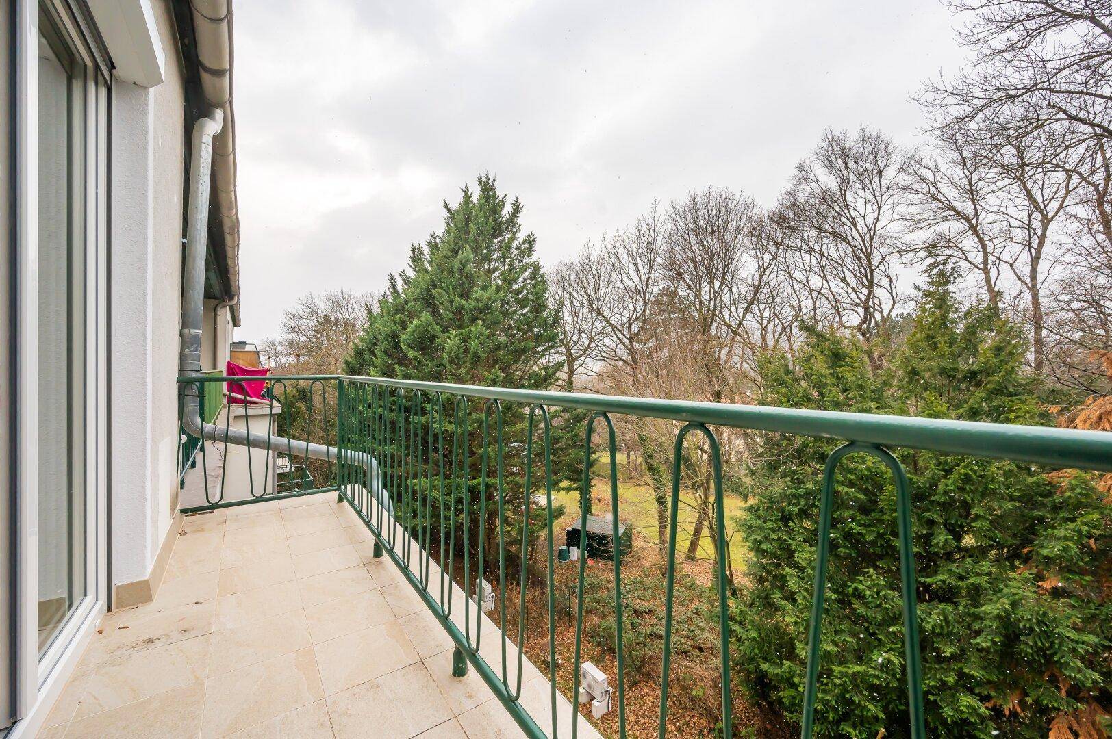 Geräumiger Balkon mit Fliesenboden und weitem Blick ins Grüne.