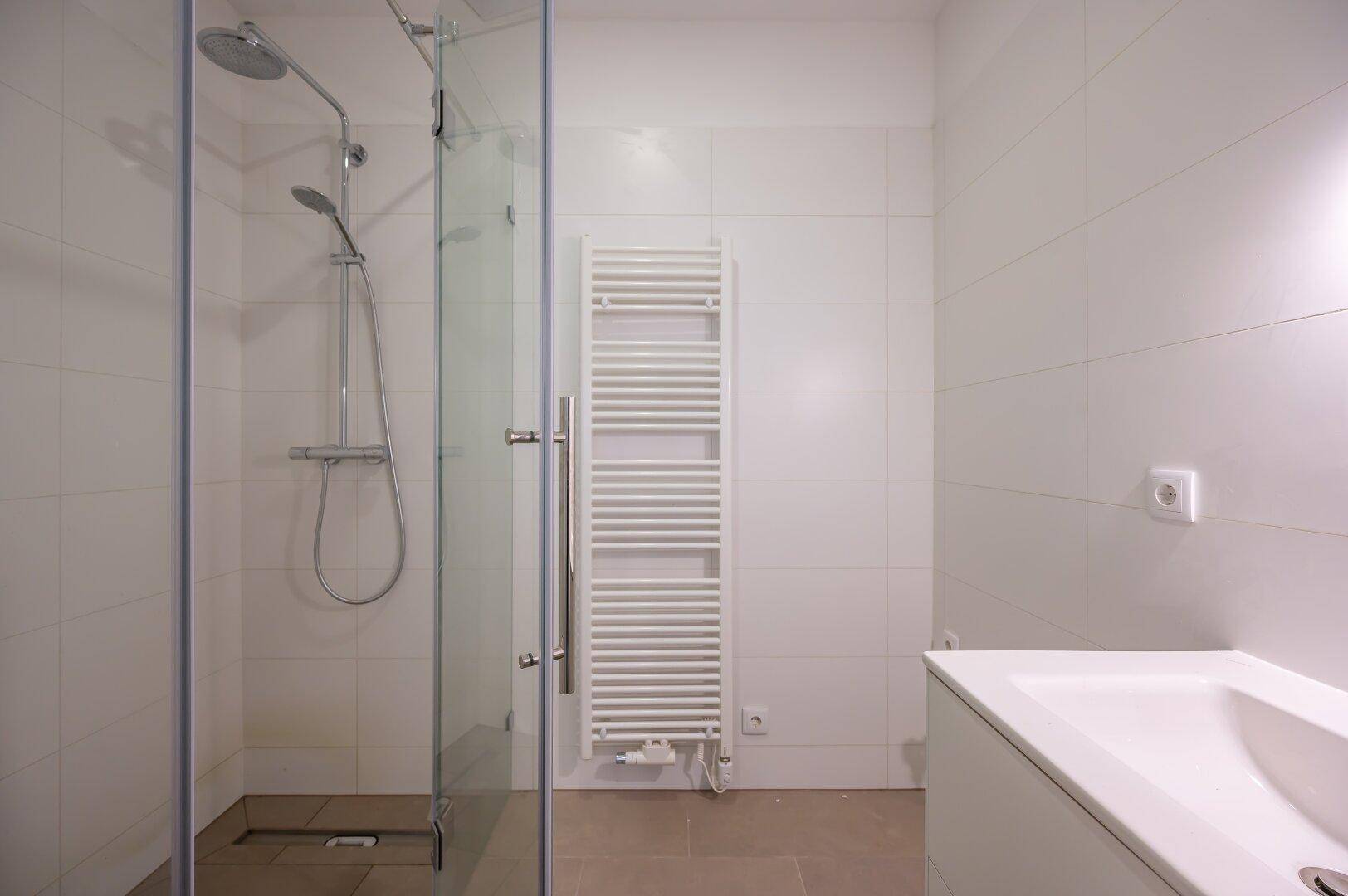 Modernes Badezimmer mit Duschkabine, Handtuchheizkörper und Waschtischunterschrank.
