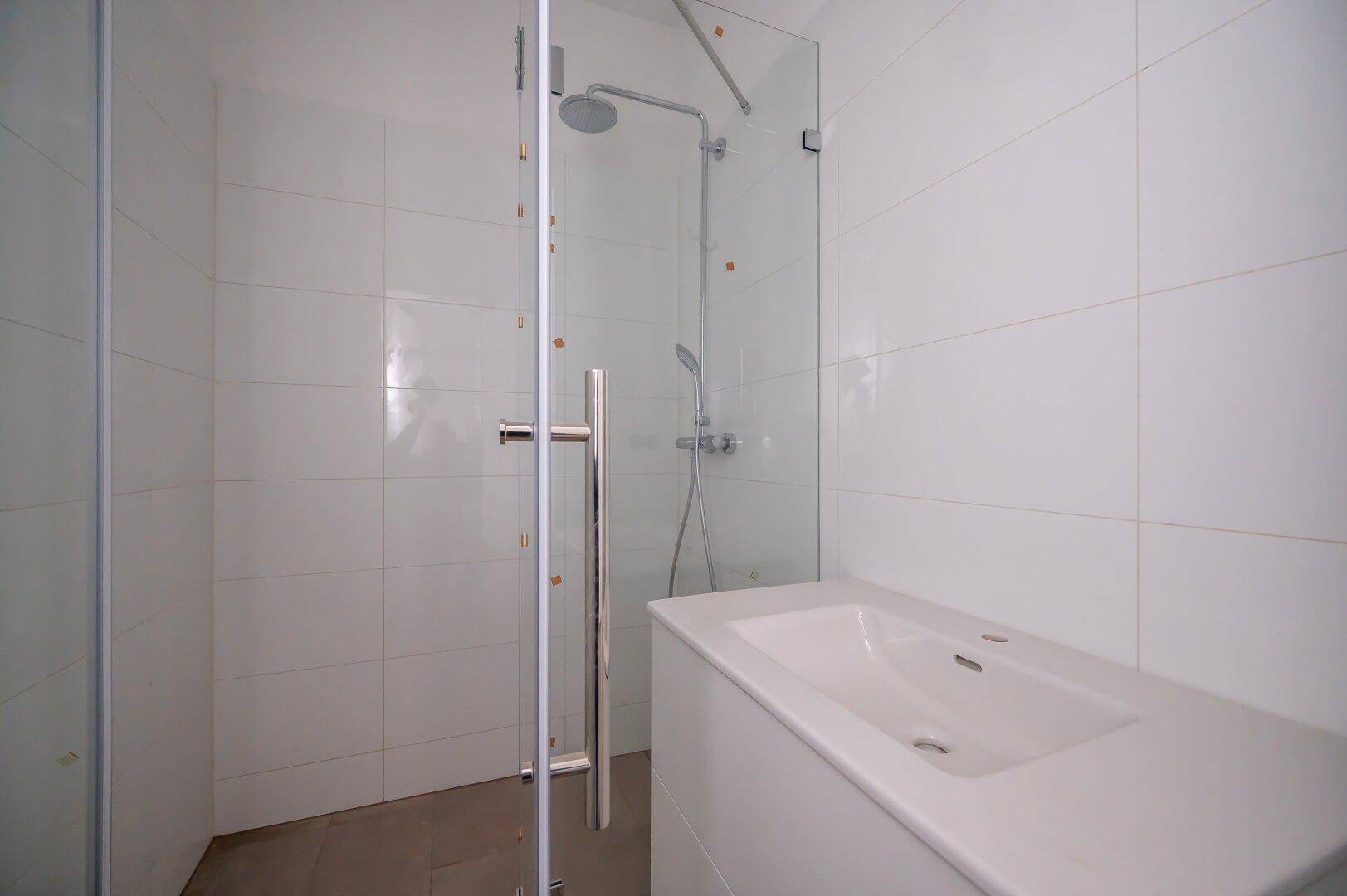 Modernes Badezimmer mit begehbarer Dusche, Glasabtrennung und einem einzelnen Waschbecken.