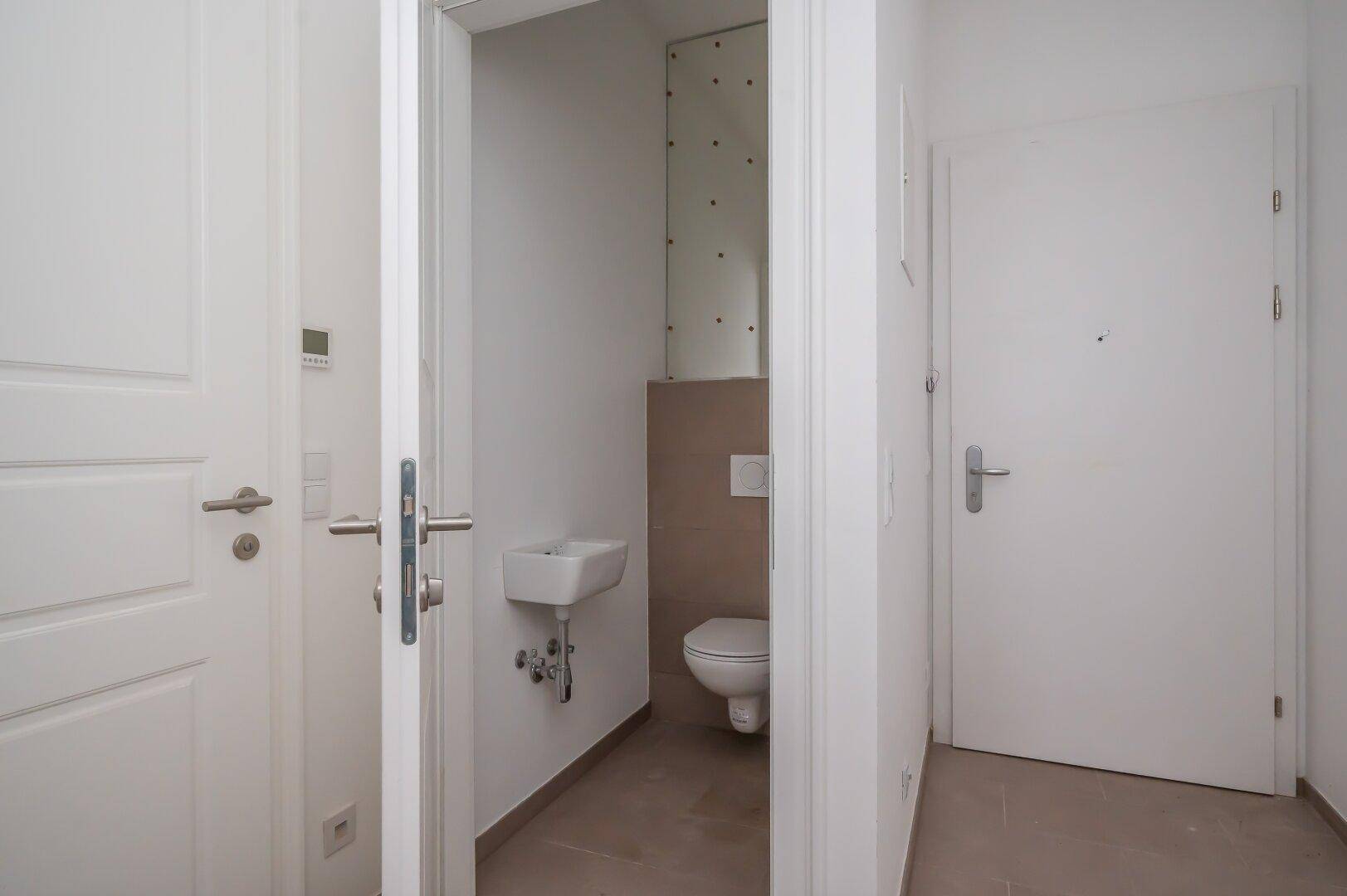 Kompaktes Gäste-WC mit wandhängender Toilette und kleinem Handwaschbecken, funktional und modern.