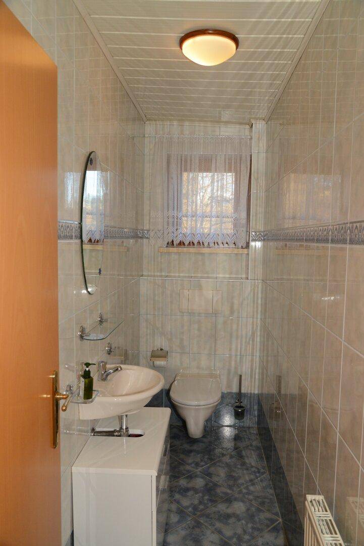 Kleines Gäste-WC mit WC, Waschbecken und Fenster, komplett gefliest.