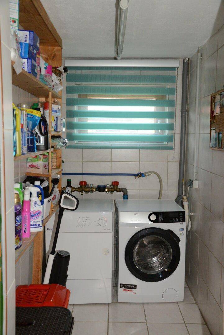 Praktischer Hauswirtschaftsraum mit Waschmaschine, Trockner und Regalen für Vorräte.
