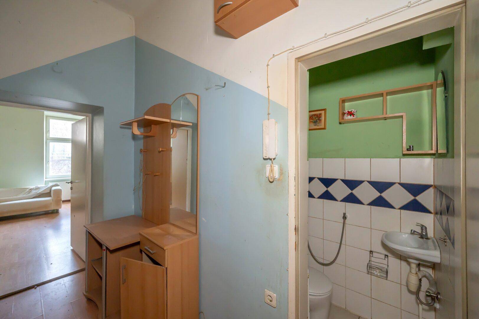 Kleines Gäste-WC mit Waschbecken und WC, direkt vom Flur zugänglich, renovierungsbedürftig.