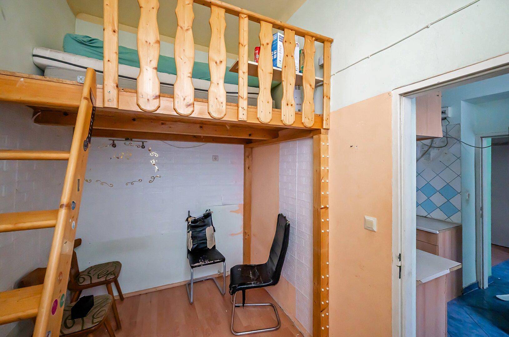 Kleiner Raum mit Hochbett und Holzleiter, ideal als Schlaf- oder Arbeitsbereich, mit Zugang zur Küche.