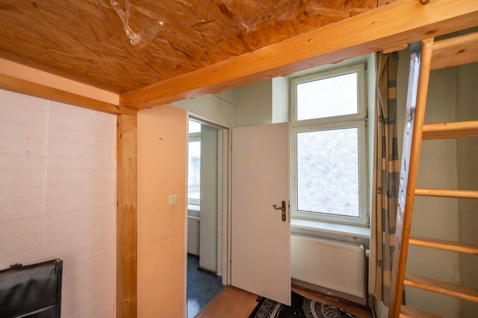 Zimmer mit Holzbalken und Fenster, bietet Potenzial für eine gemütliche Gestaltung nach Renovierung.