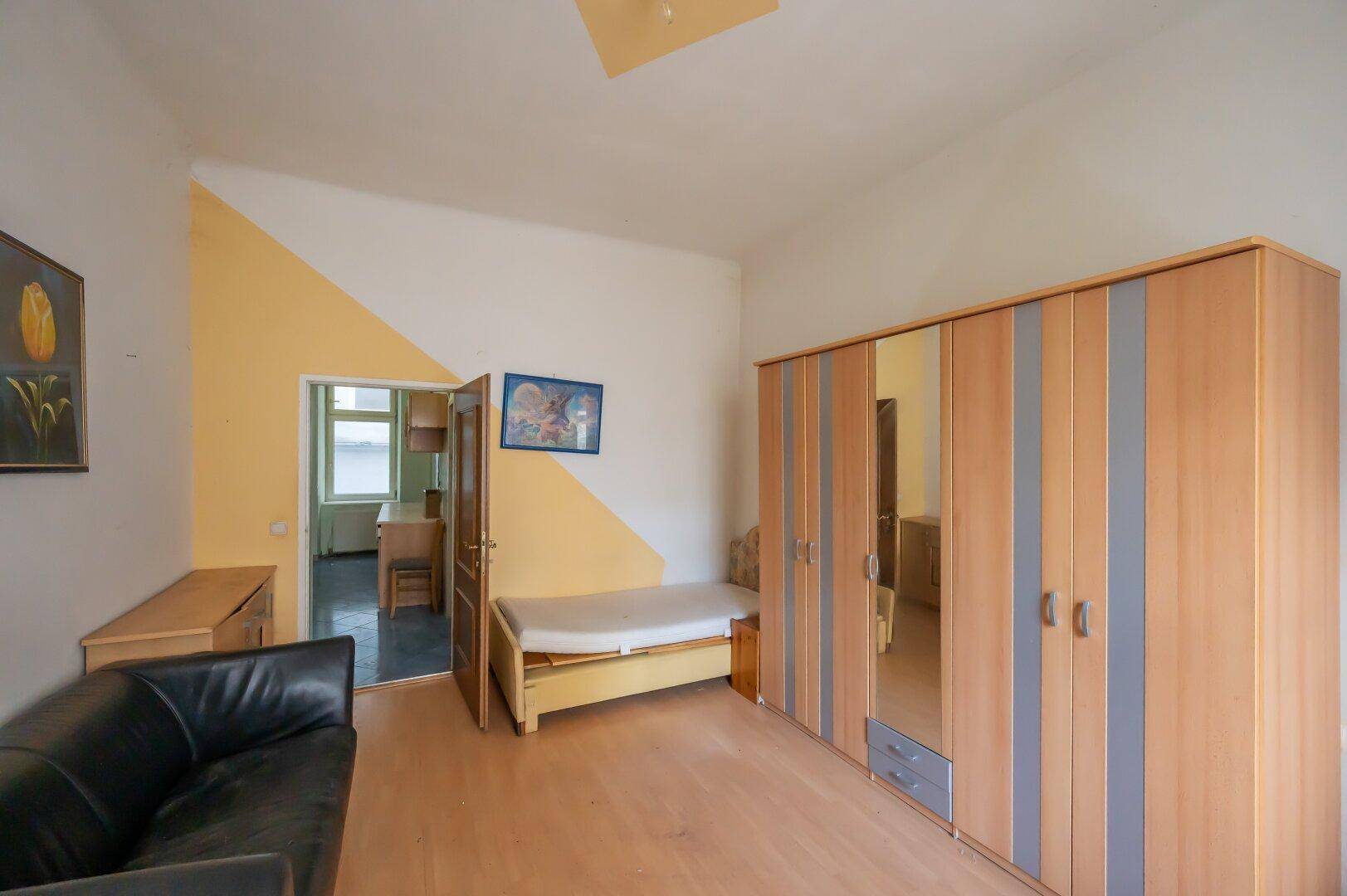 Schlafzimmer mit Laminatboden, Kleiderschrank und Zugang zu einem weiteren Raum, ideal für eine Familie.
