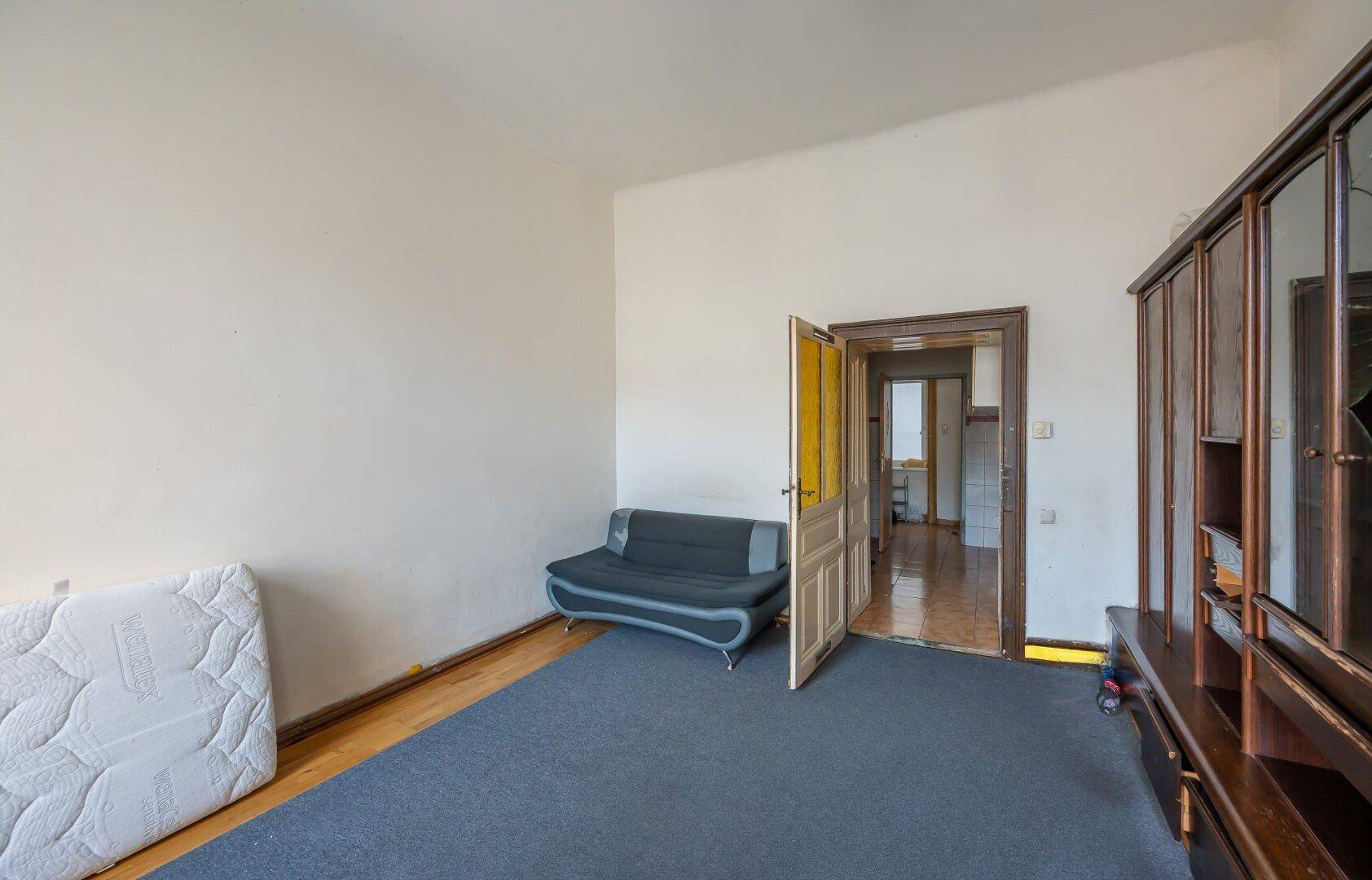 Heller Wohnraum mit Parkettboden, einem Sofa und Zugang zu weiteren Zimmern.