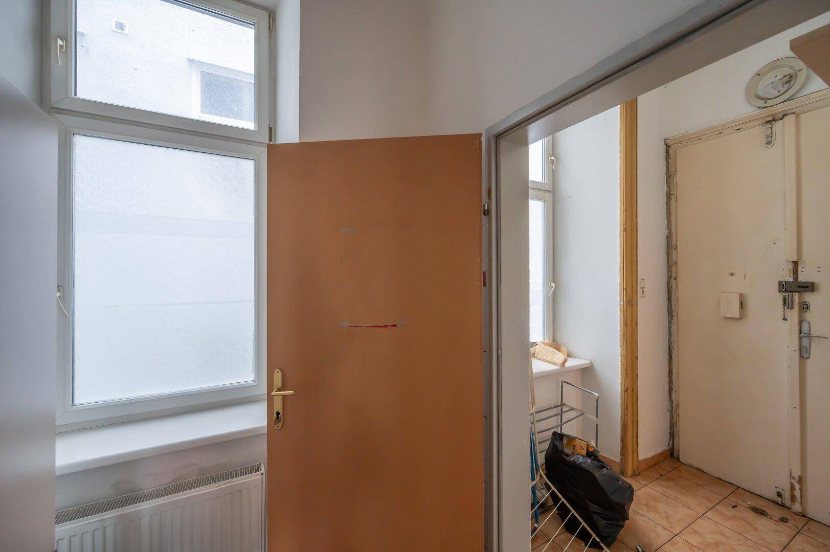 Eingangsbereich mit Fliesenboden, mehreren Türen und Fenstern mit Milchglas.
