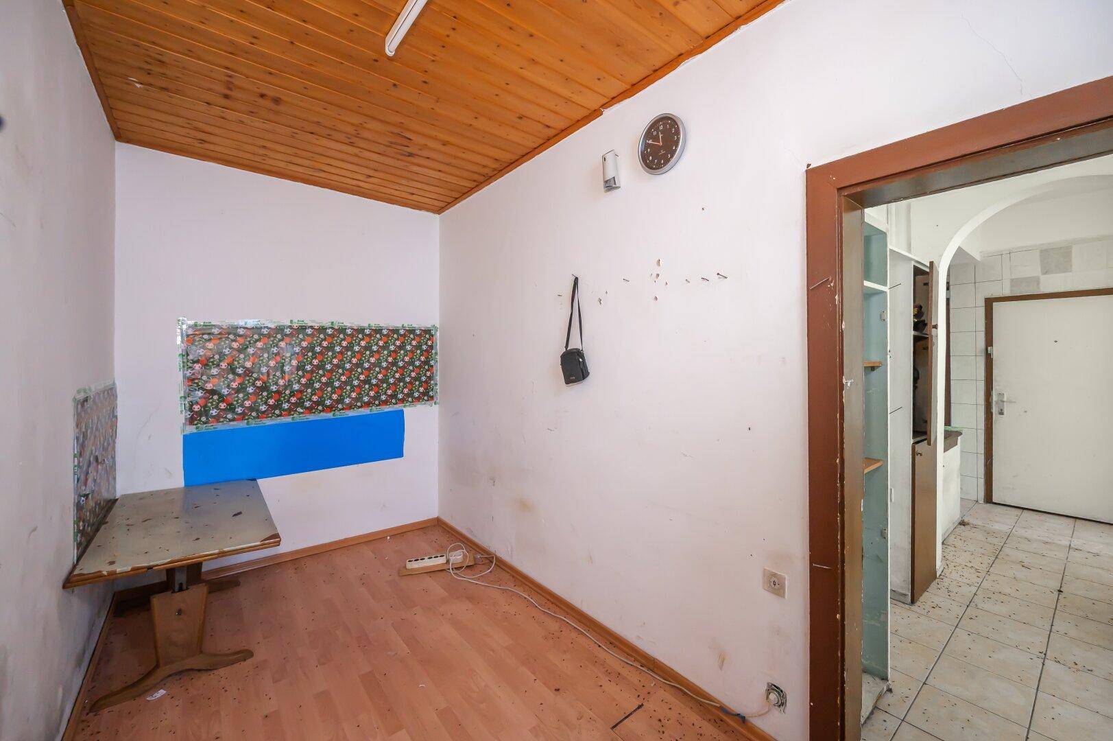 Kleiner Raum mit Holzdecke und Holzboden, der eine umfassende Renovierung erfordert.
