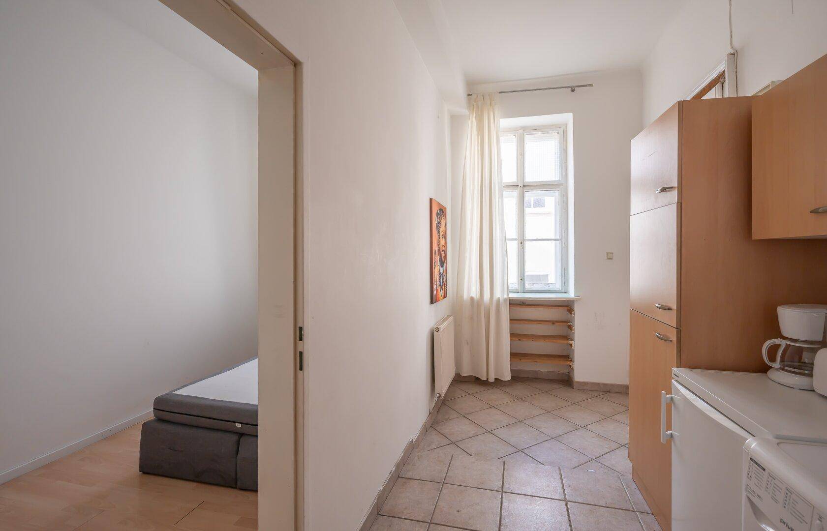 Heller Flur mit Fliesenboden, der zu einem Schlafzimmer und einer Küchenzeile führt.