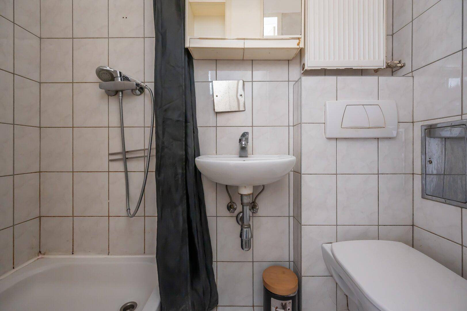 Gefliestes Badezimmer mit Badewanne, Dusche, Waschbecken und Toilette.