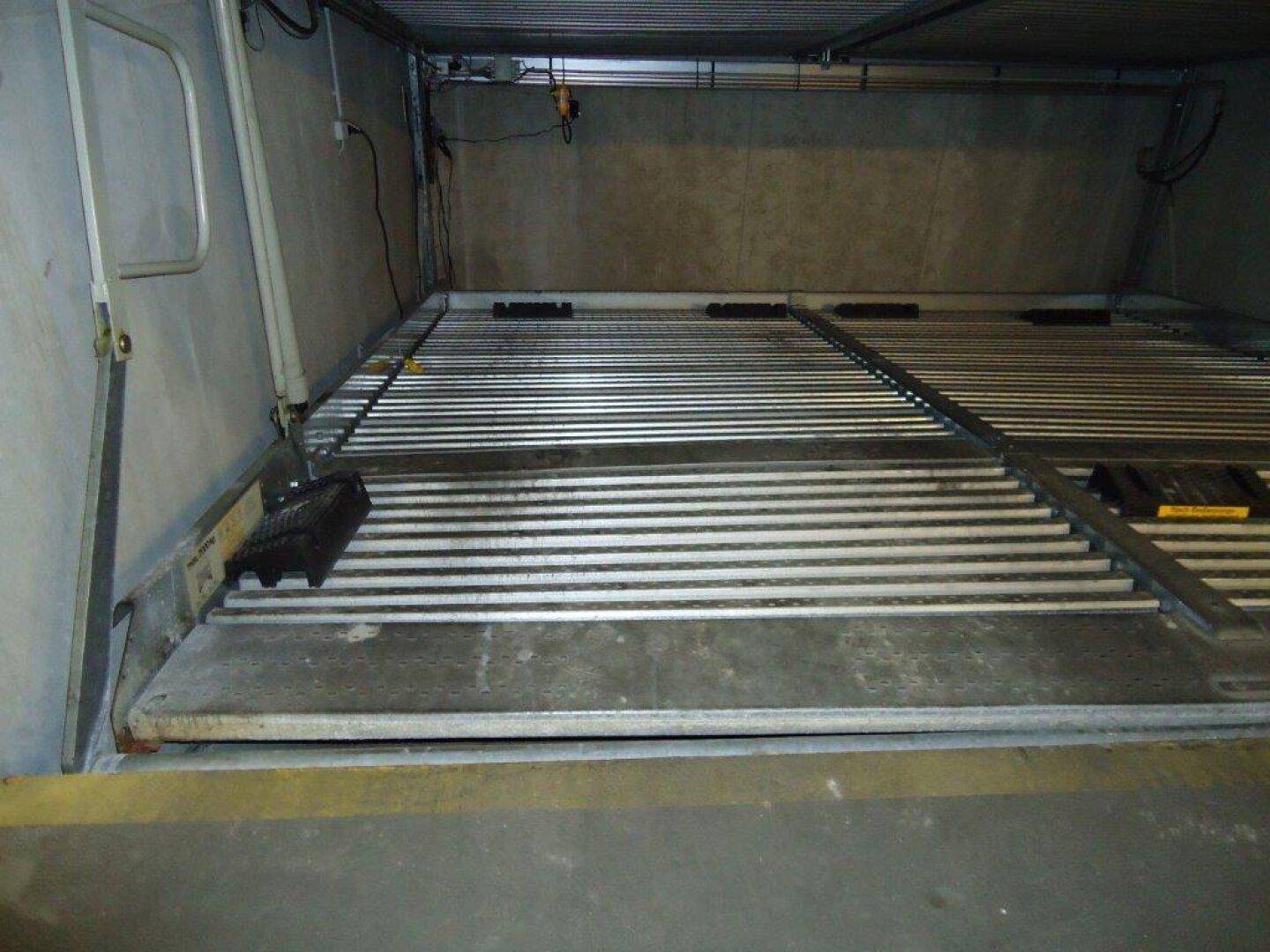 Leere untere Plattform eines mechanischen Parksystems in einer Tiefgarage, bereit für ein weiteres Fahrzeug.