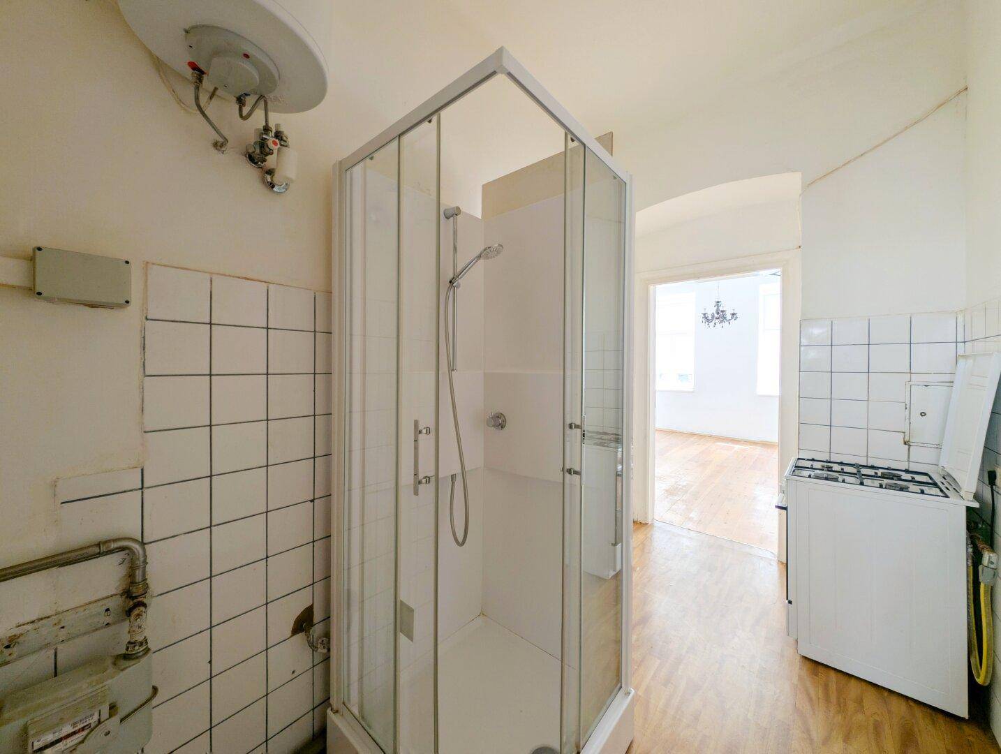 Kombinierter Raum mit Duschkabine, Warmwasserbereiter und Blick in den angrenzenden Wohnbereich.