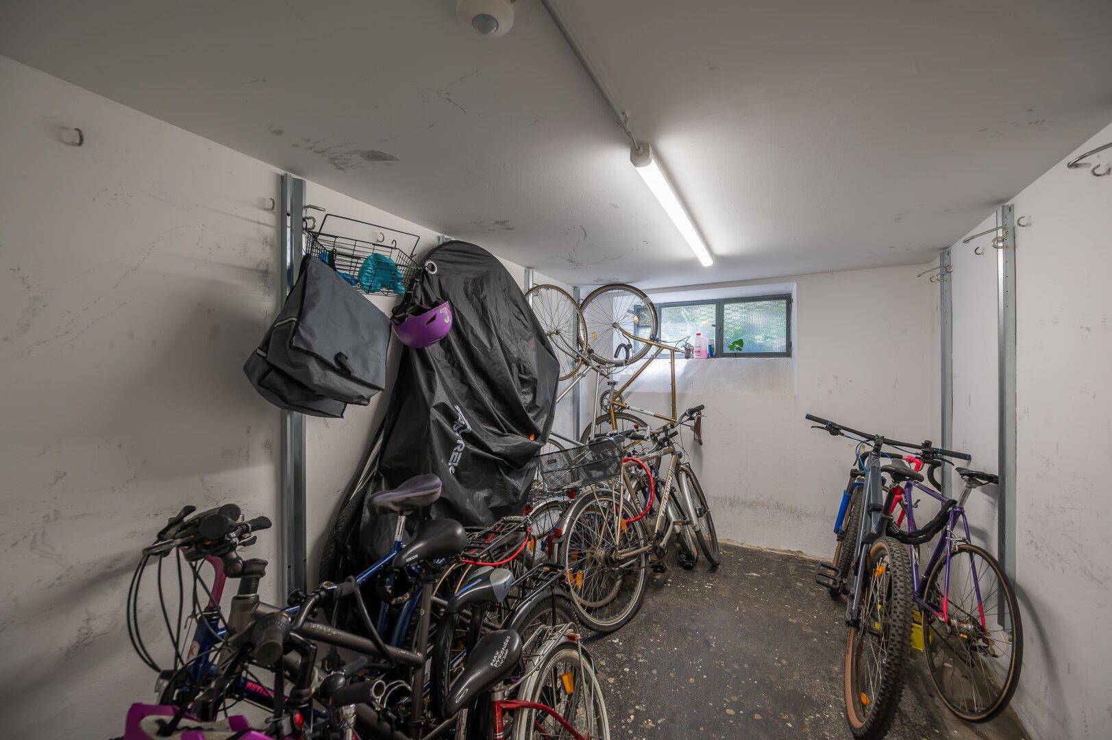 Fahrradraum im Kellergeschoss mit mehreren Fahrrädern und einem kleinen Fenster.