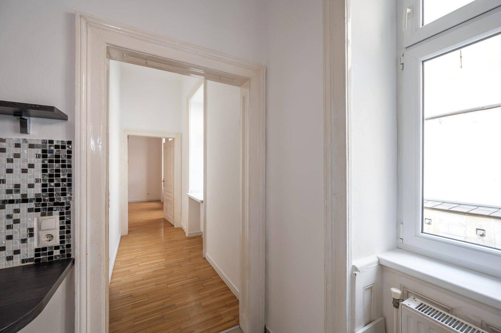Heller Flur mit Holzboden, der zu weiteren Zimmern der Wohnung führt.