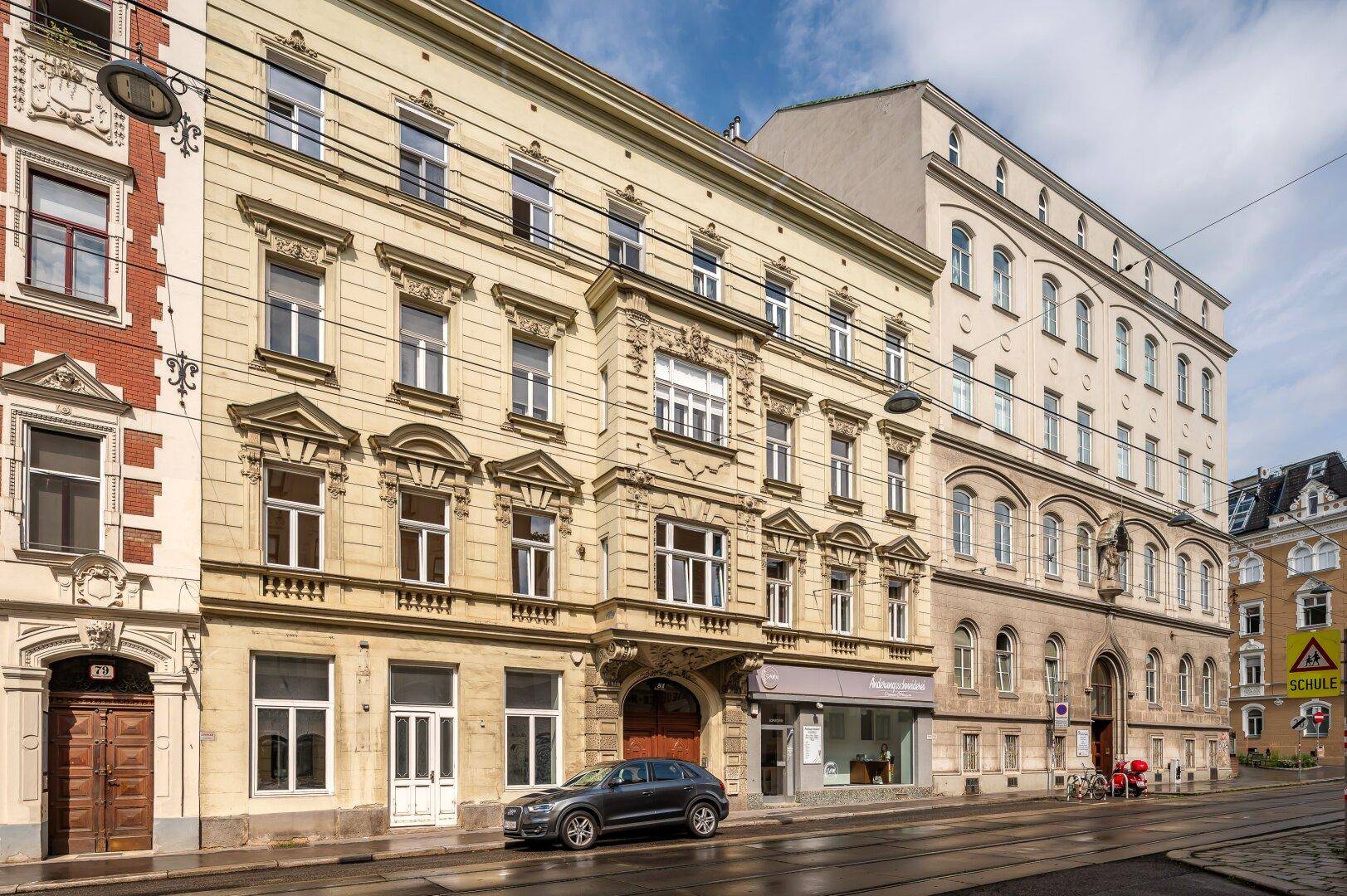 Prächtige Fassade eines Altbaus mit detaillierten Verzierungen und großen Fenstern.