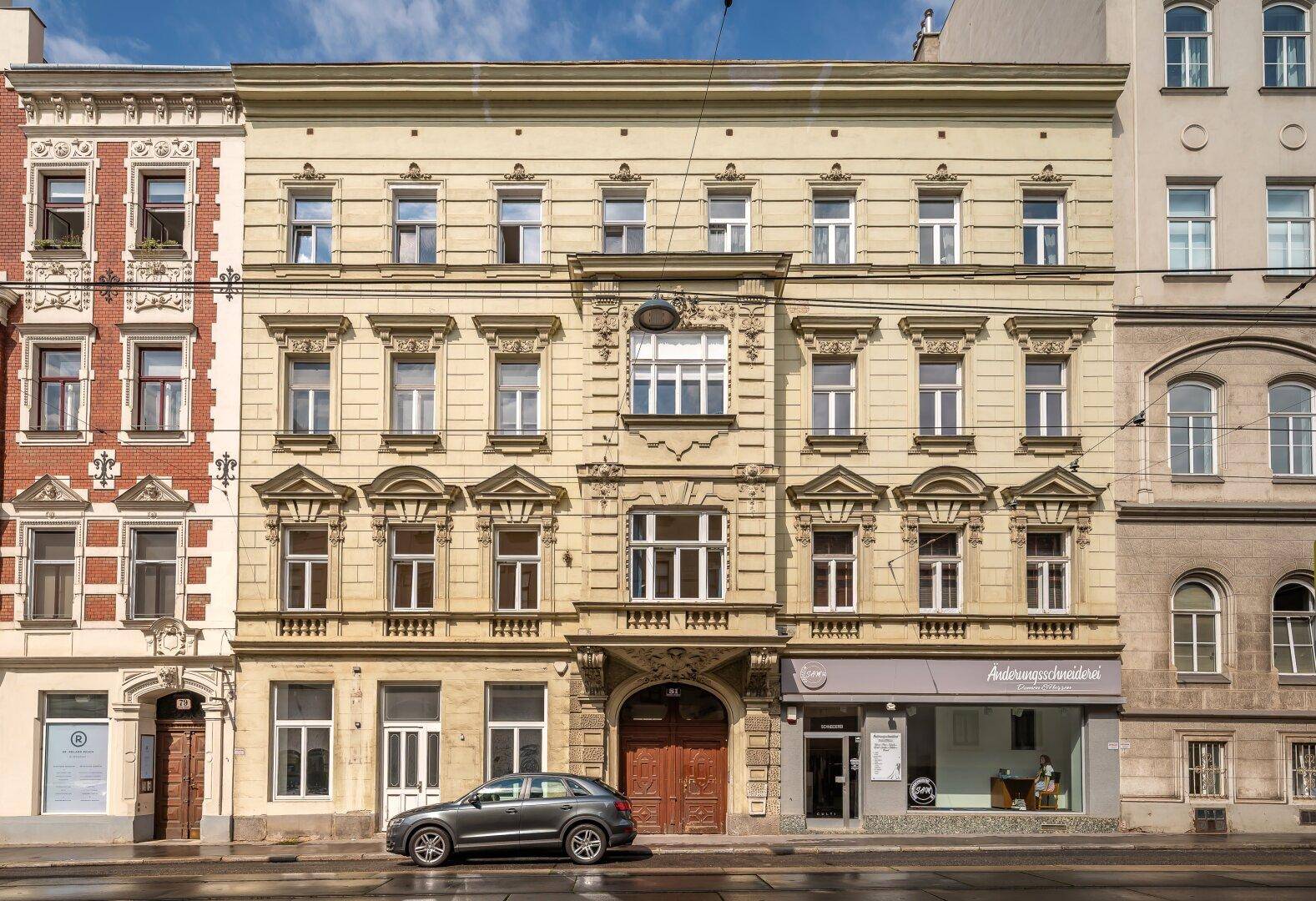 Historische Gebäudefassade mit klassischer Architektur und Geschäften im Erdgeschoss.