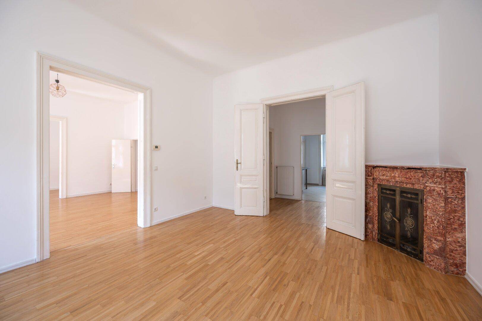 Helles Zimmer mit Holzboden und einem dekorativen Kamin, der Charakter verleiht.