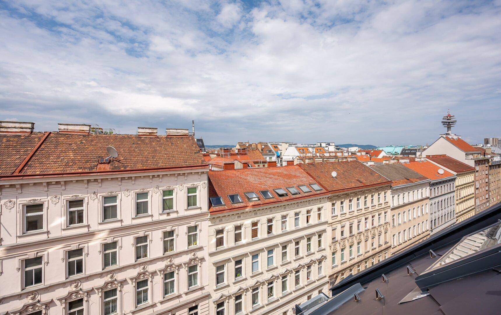 Historische Stadtansicht mit alten Gebäudefassaden und roten Ziegeldächern.