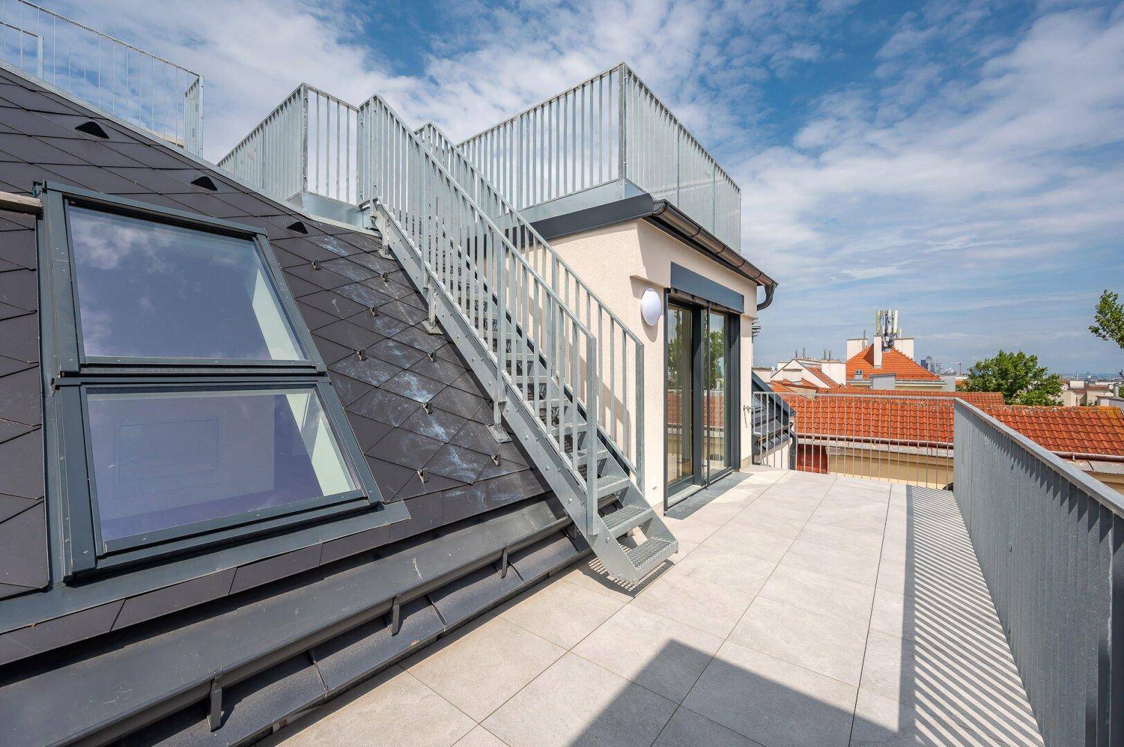 Außenansicht des Gebäudes mit Dachterrasse, Treppe und Dachfenstern.