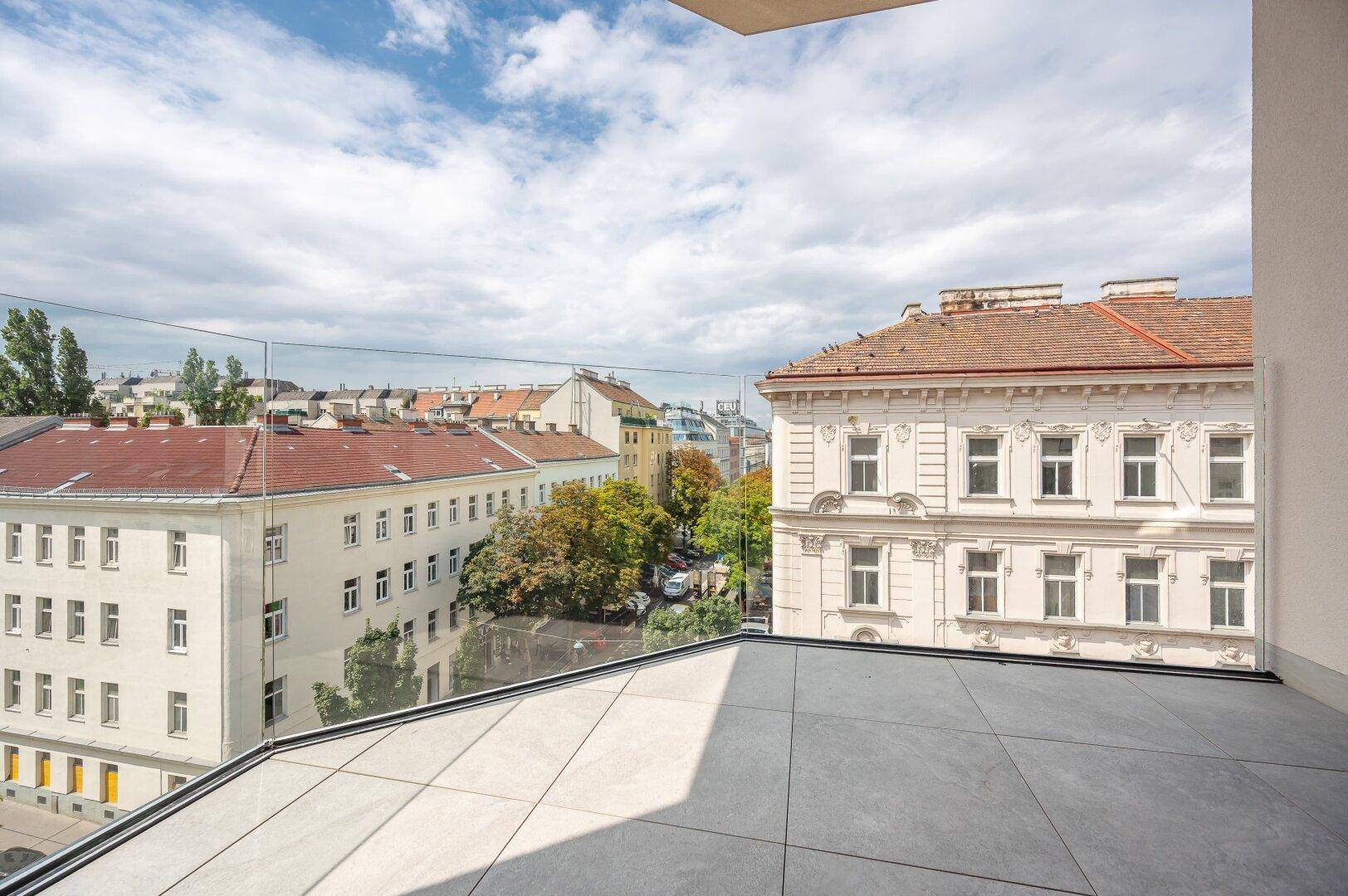 Geräumiger Balkon mit Fliesenboden und Glasgeländer, ideal für entspannte Stunden im Freien.