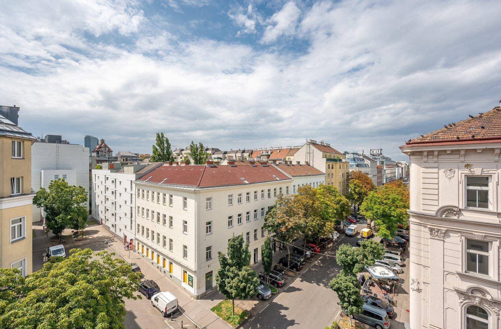 Überblick über ein Stadtviertel mit verschiedenen Gebäuden, grünen Bäumen und geparkten Fahrzeugen.