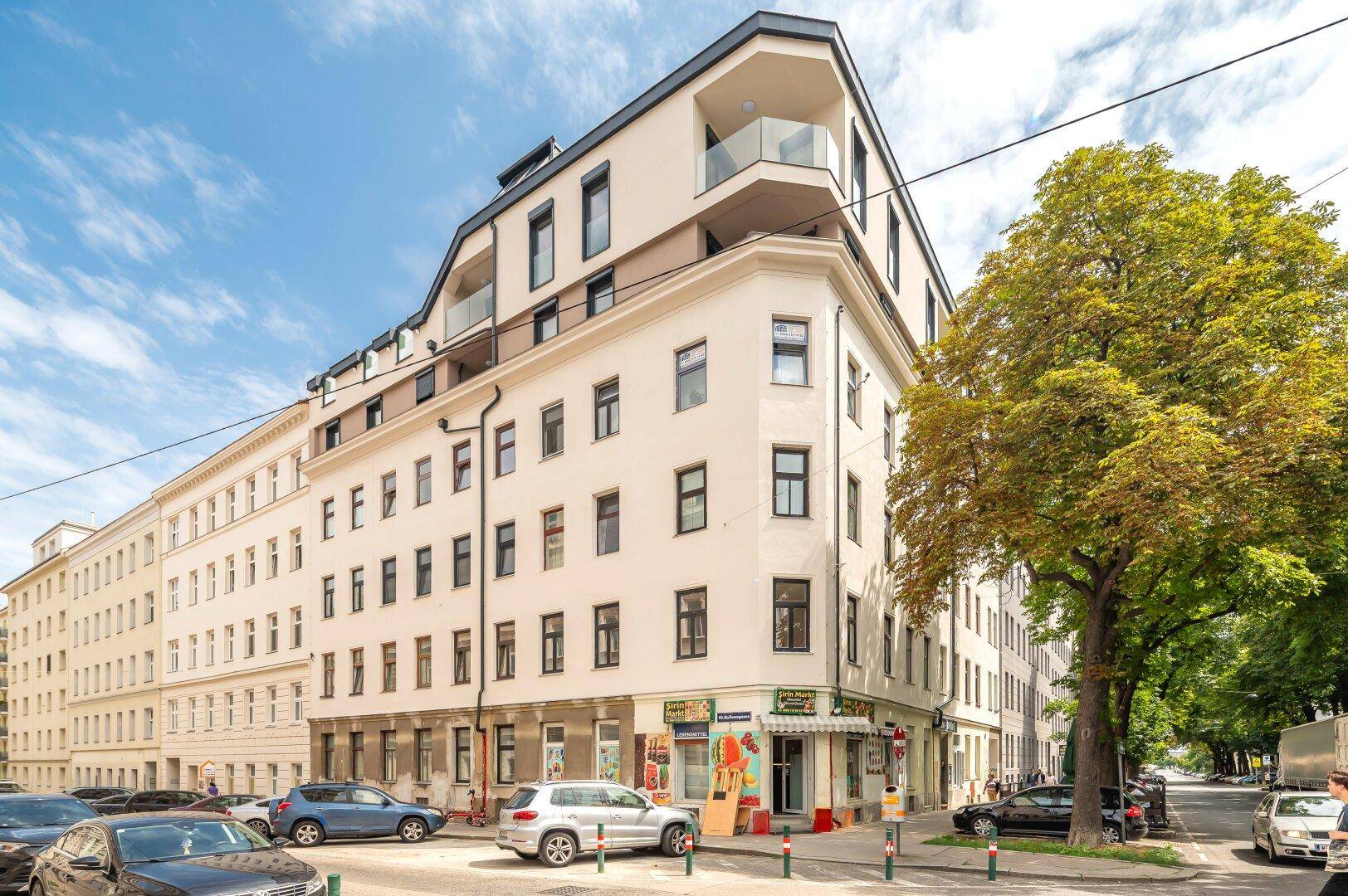 Modernes Eckgebäude mit Geschäften im Erdgeschoss und Balkonen in der Stadt.